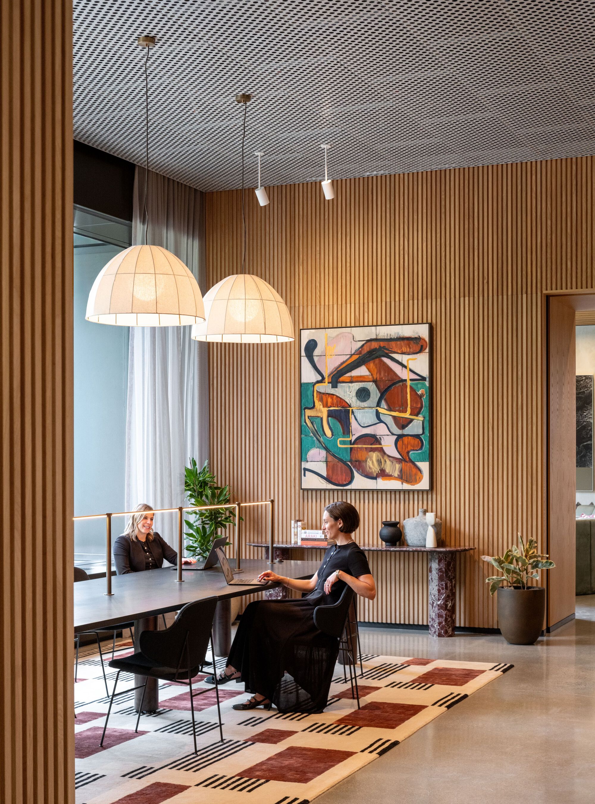 Dining area with vertical wood slat walls, perforated metal ceiling, and patterned geometric floor inlay