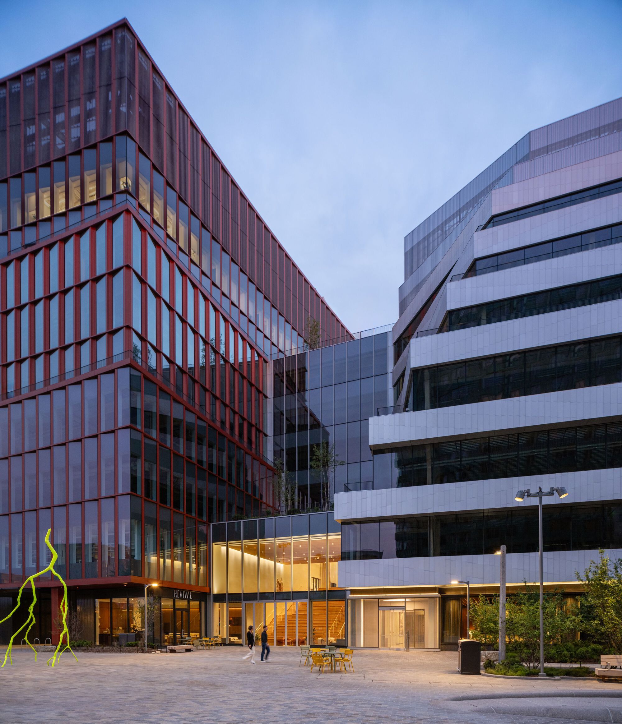 Courtyard view between vertical brick facade and horizontal banded facade at dusk