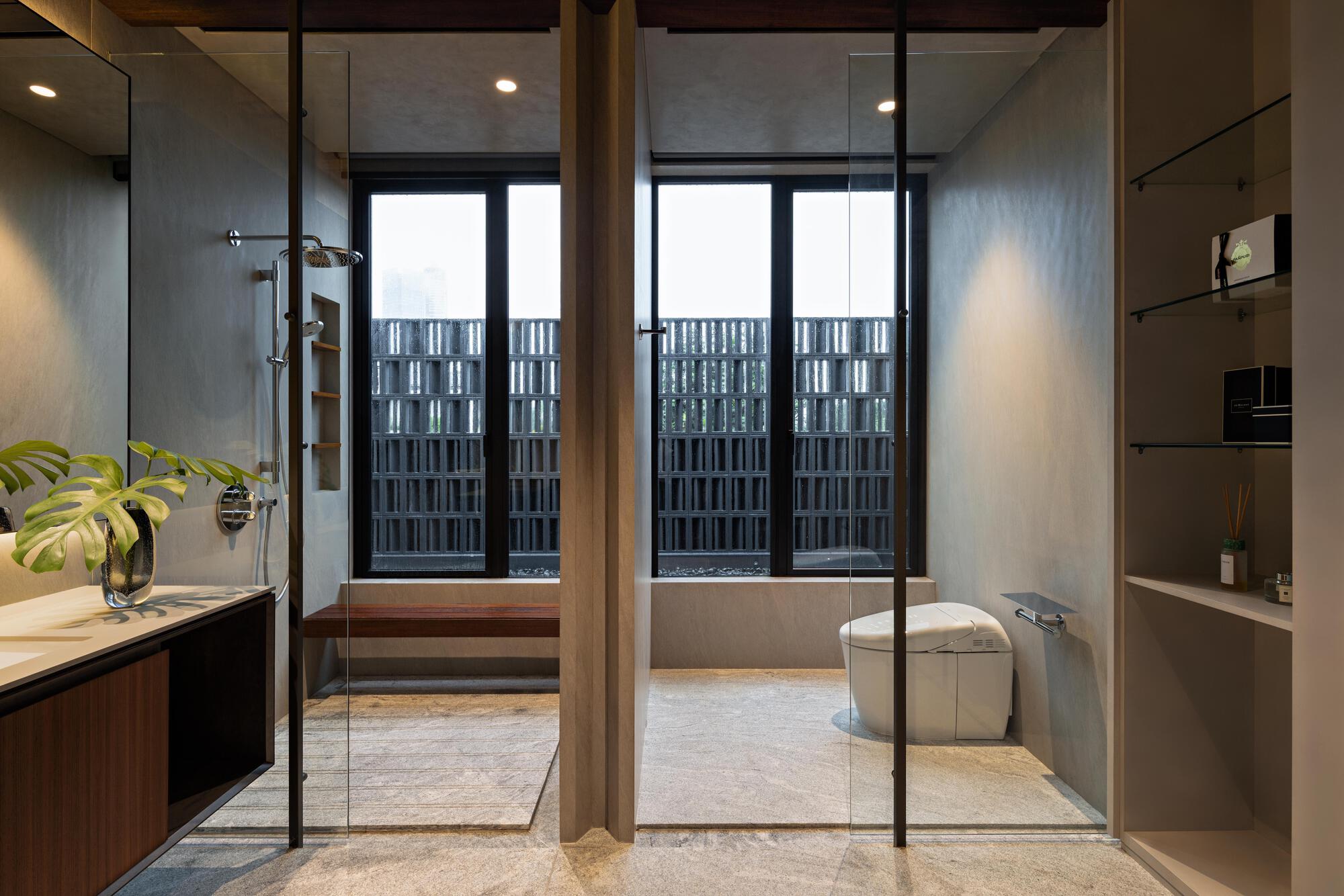Bathroom with glass shower enclosure and freestanding tub overlooking patterned metal privacy screens beyond windows