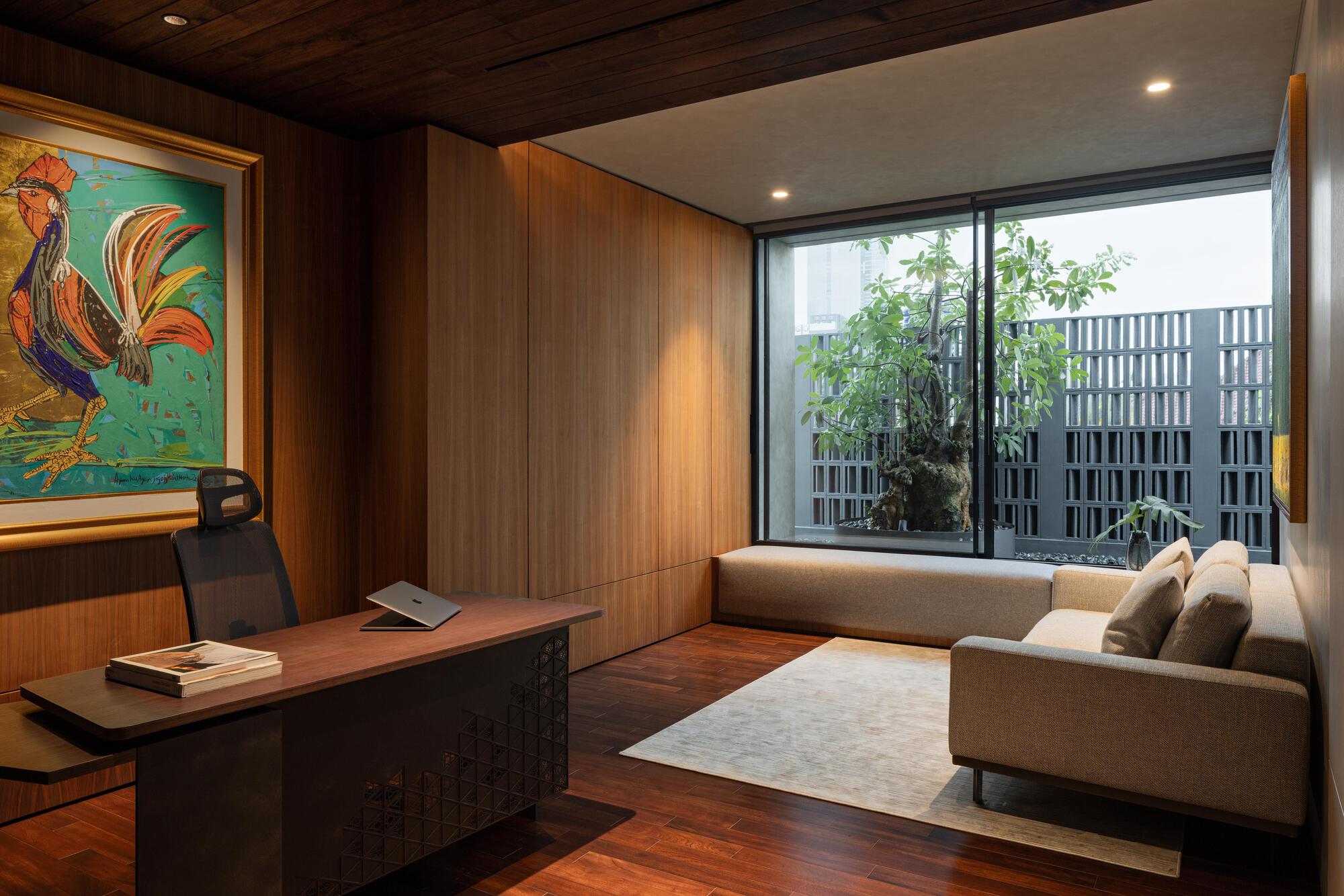 Interior lounge with vertical timber paneling and glazed doors opening to a screened courtyard with vegetation