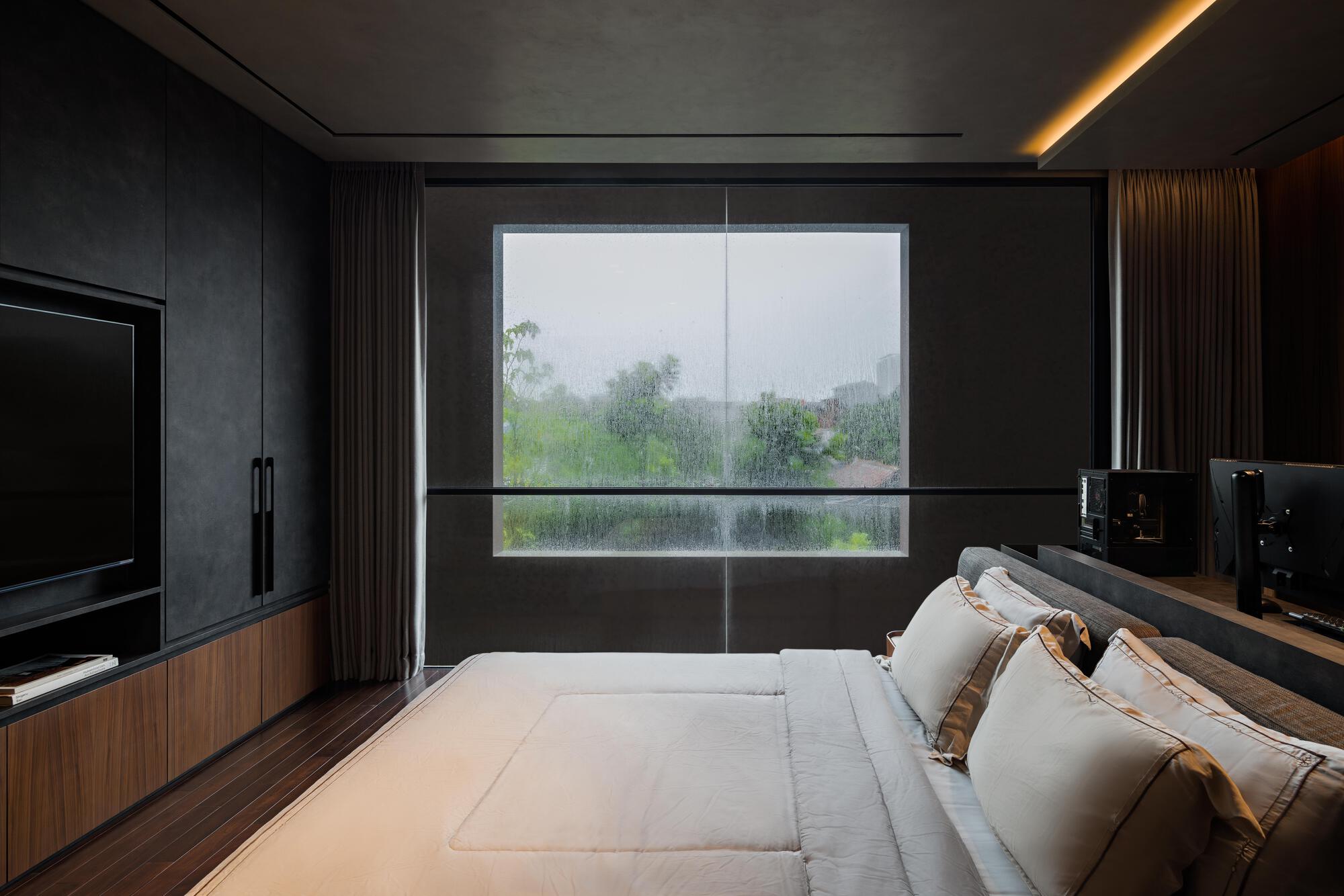 Bedroom with horizontal ribbon window framing a misty garden view and concealed lighting in the ceiling cove