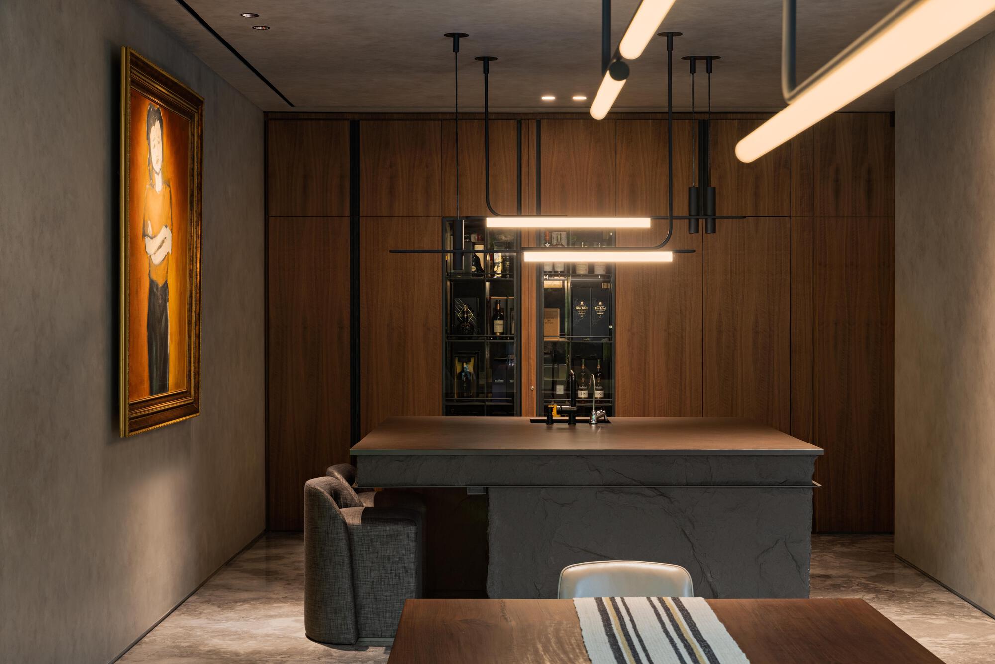 Home bar with walnut cabinetry, gray marble island, and tubular pendant lights under a wood ceiling