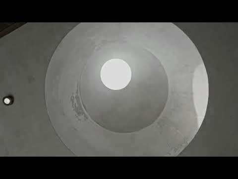 Looking up through a circular oculus in a domed concrete ceiling with concentric stepped rings