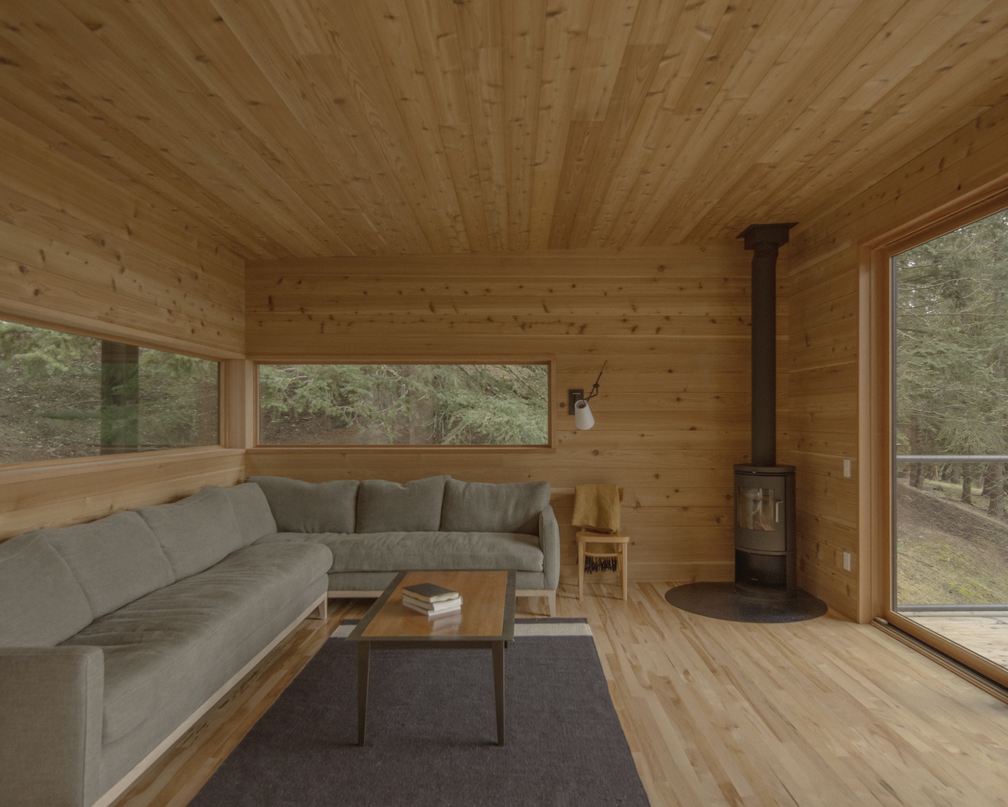 Interior living space with tongue-and-groove pine ceiling and walls, corner windows framing forest views
