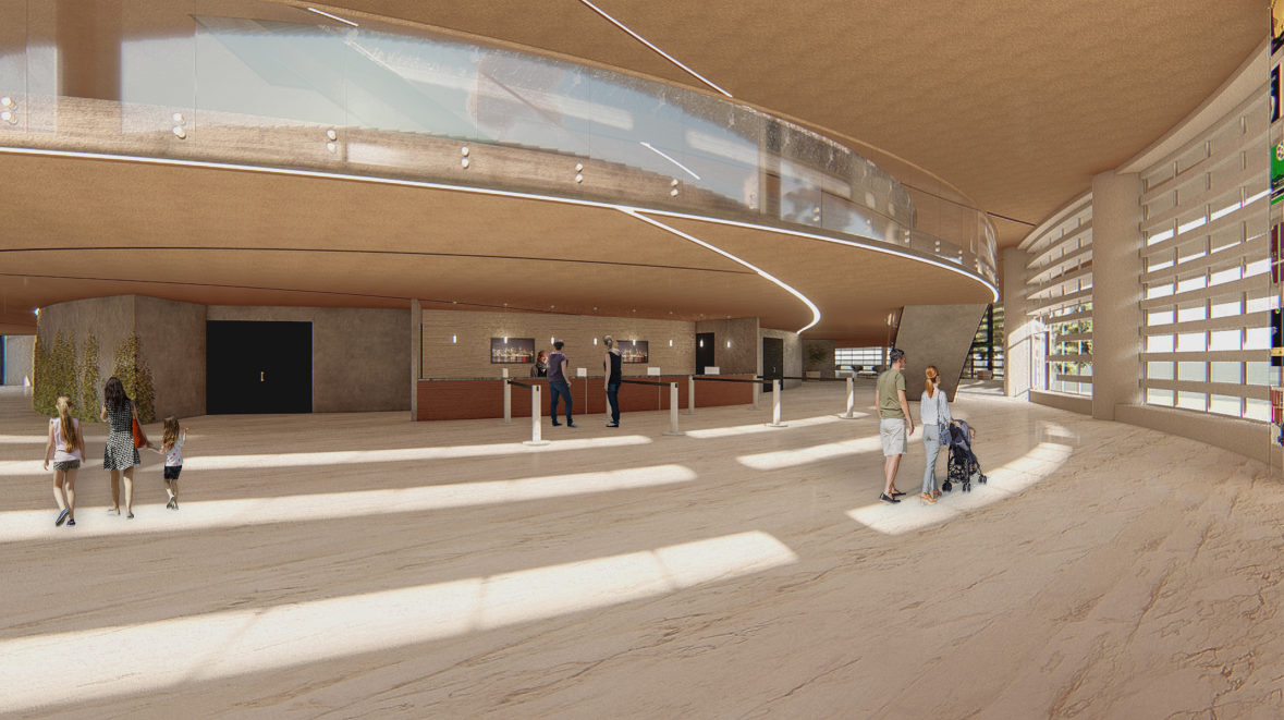 Interior lobby with curved mezzanine balcony and light-colored wood floors dotted with visitors in sunlight