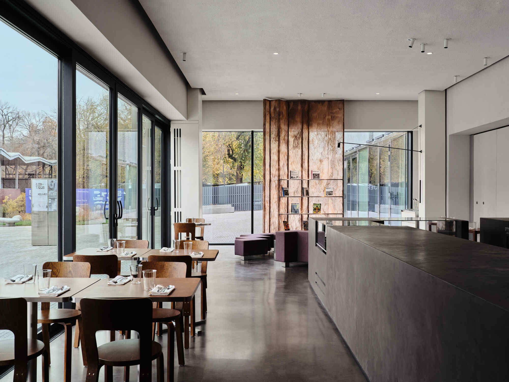 Interior cafe space with polished concrete floor, timber feature wall, and floor-to-ceiling glazing overlooking the terrace