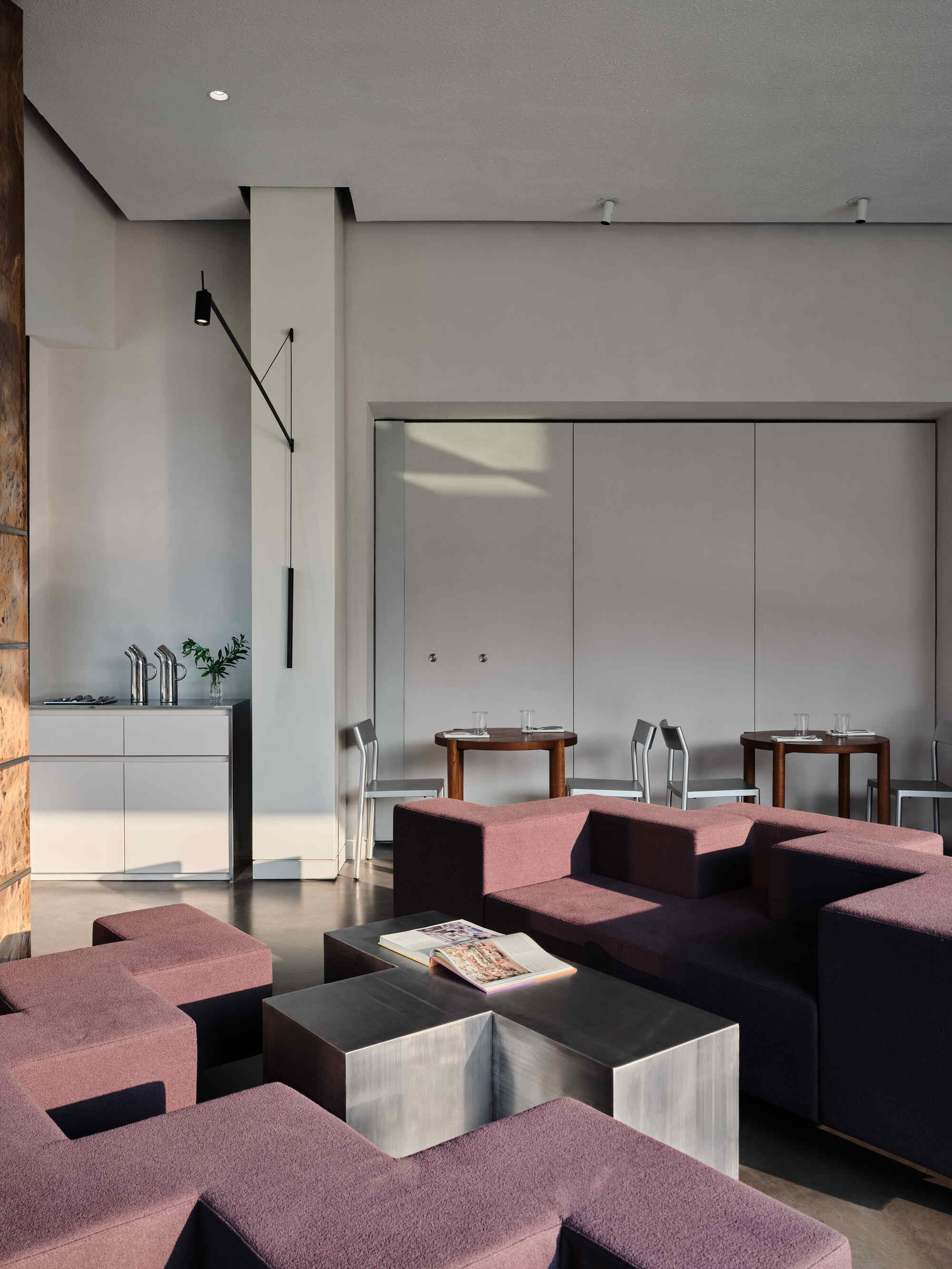 Lounge area with modular burgundy seating facing a white dining niche with recessed lighting from above