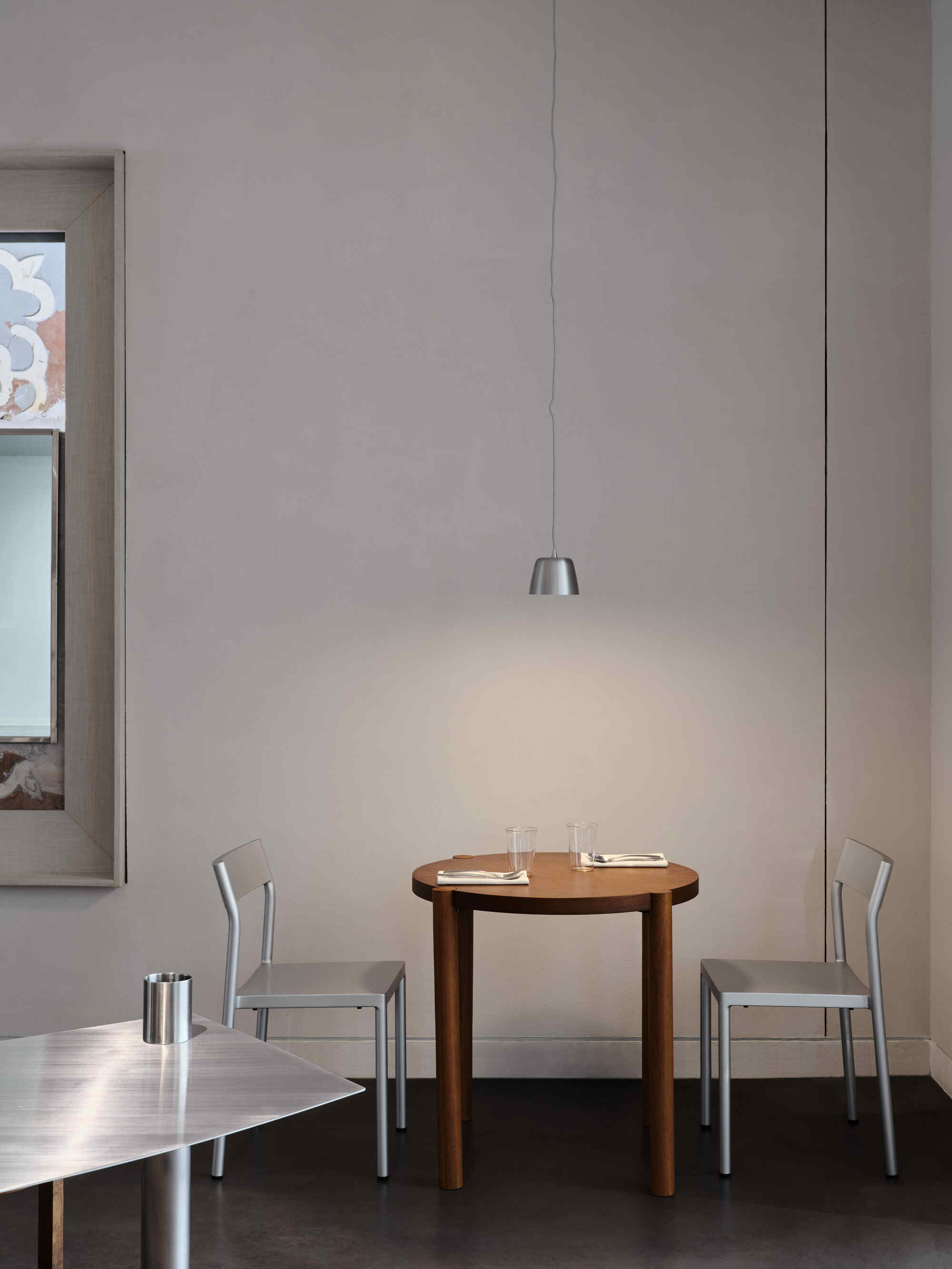 Close view of a suspended pendant fixture casting light onto a timber table with metal chairs