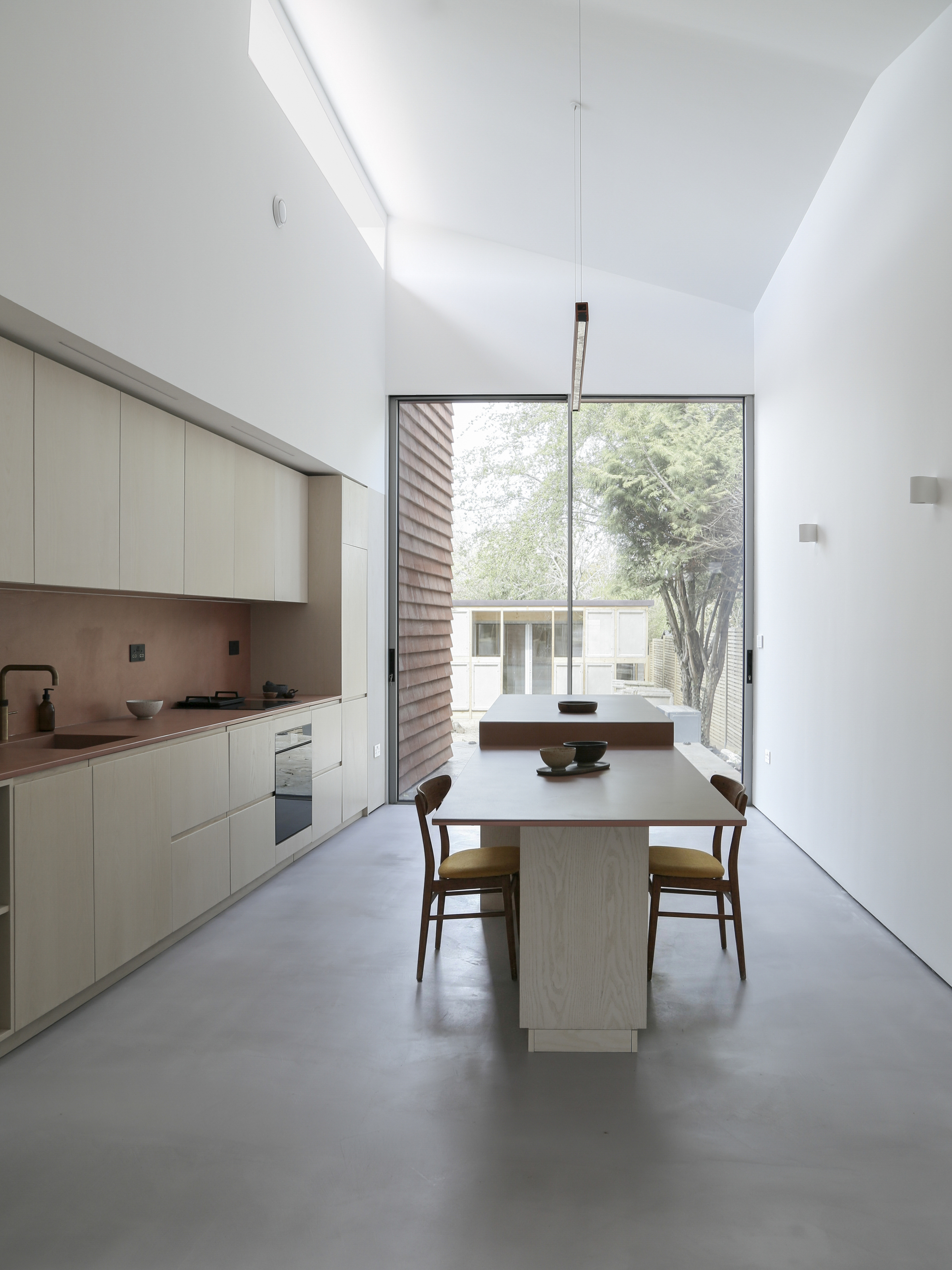 Kitchen and dining area with clerestory window, polished concrete floor and view to courtyard beyond