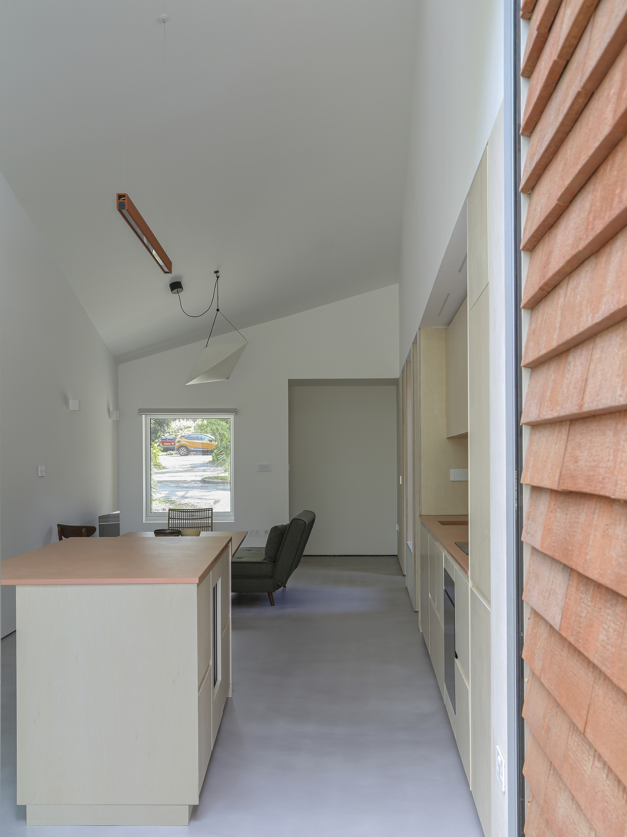 Interior view along kitchen island toward framed window opening with cedar cladding visible outside