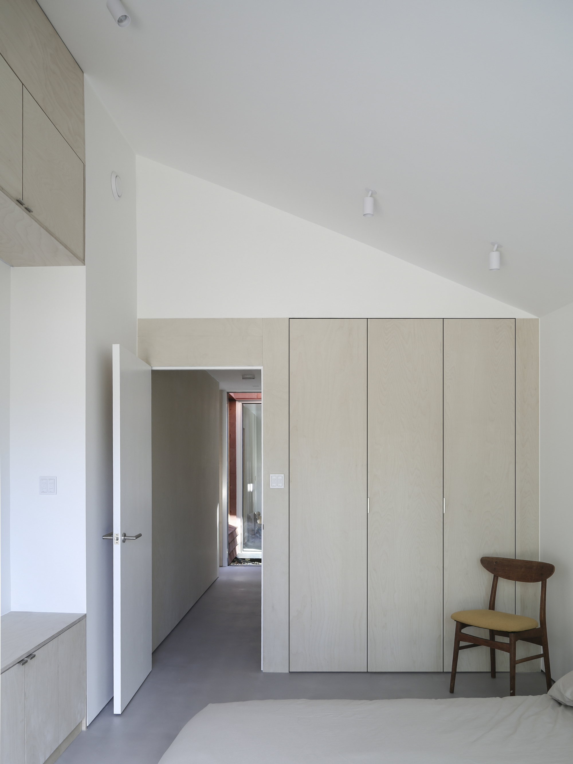 Interior corridor with pale plywood cabinetry and a view through to daylit rooms beyond