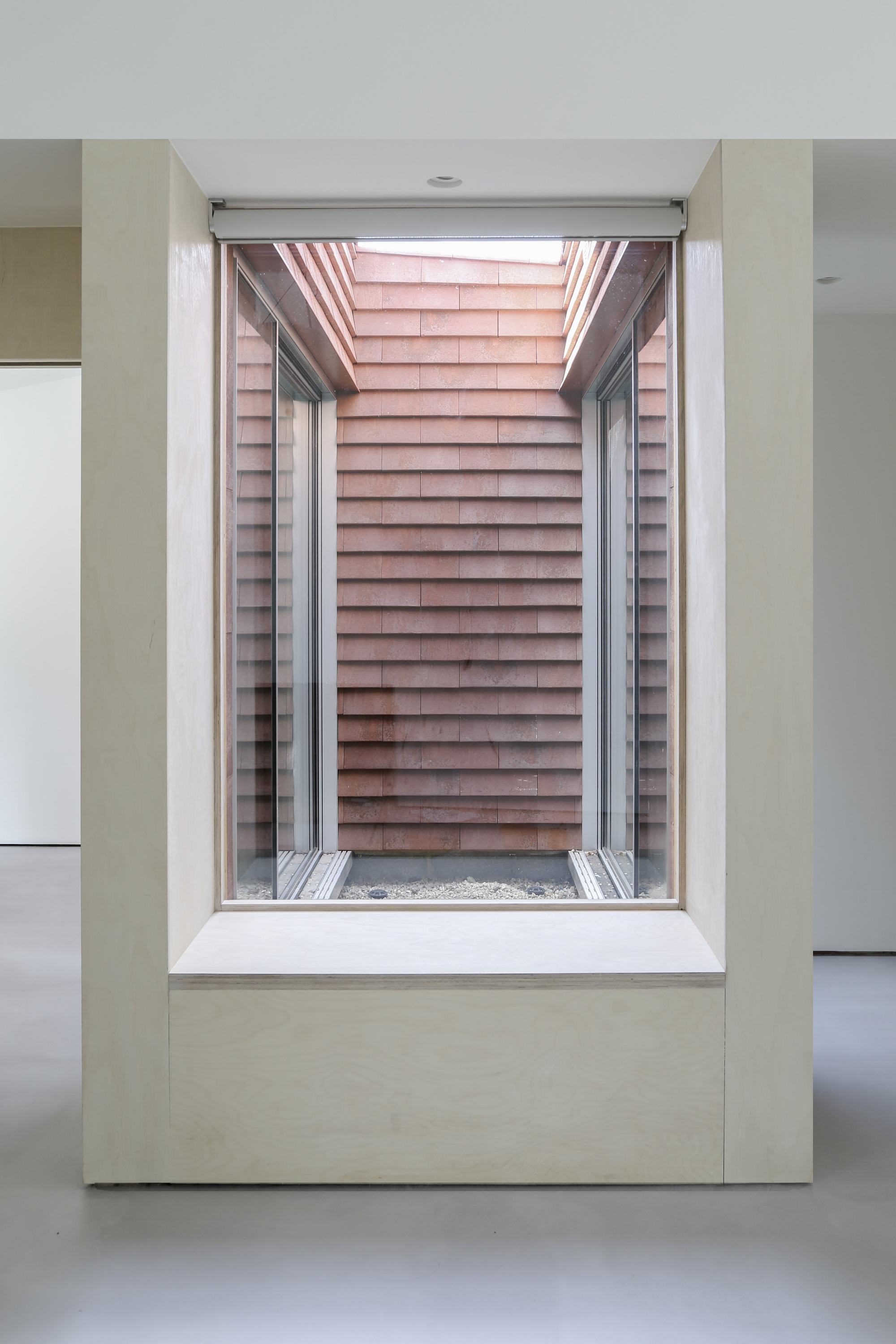 Interior courtyard framed by white-painted walls with horizontal timber cladding and a skylight overhead