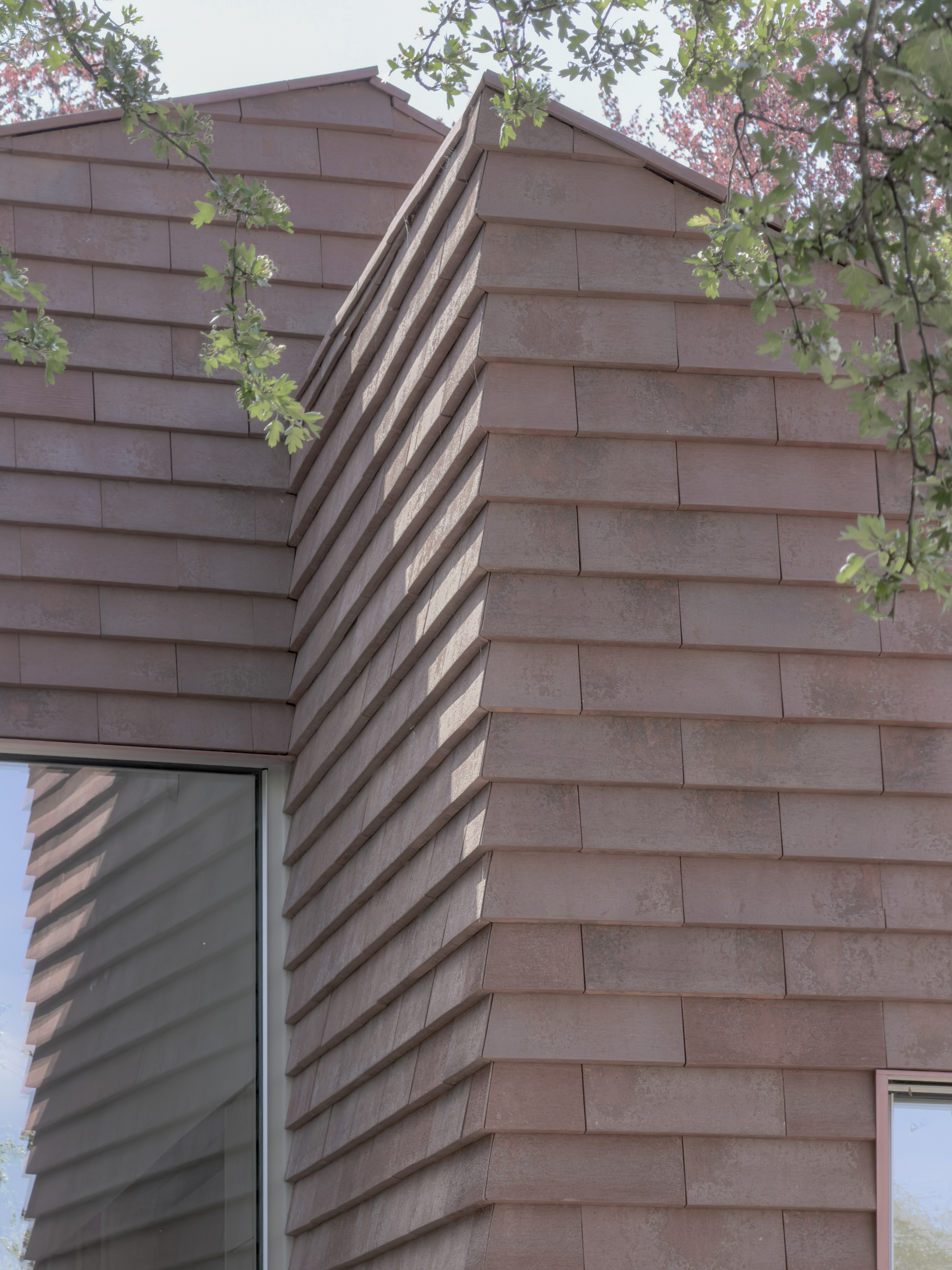 Gabled roof with horizontal timber shingles and deep shadow slot between two volumes