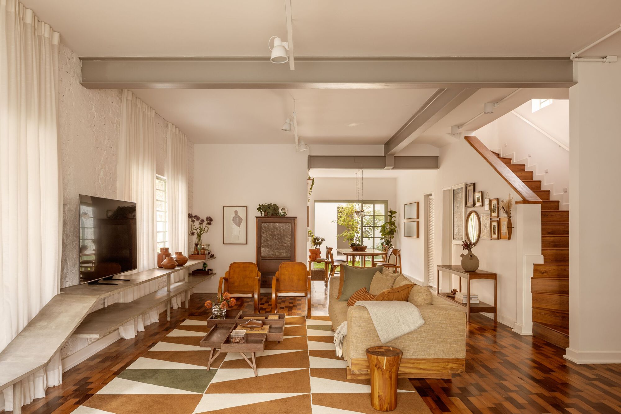 Open-plan living space with chequered tile floor and exposed timber ceiling beams in afternoon light