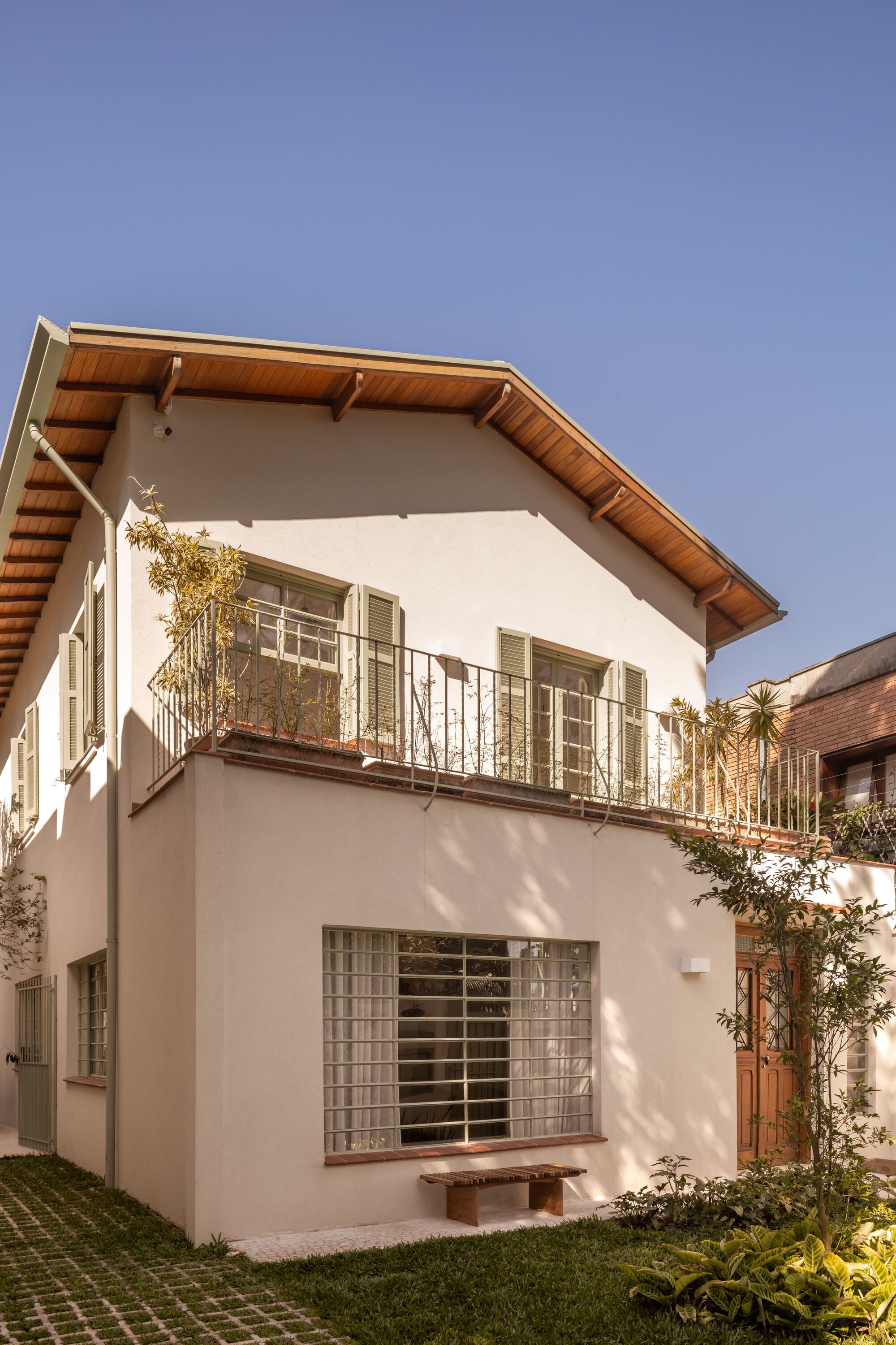 White rendered facade with glass block windows and timber eave soffit under a clear sky