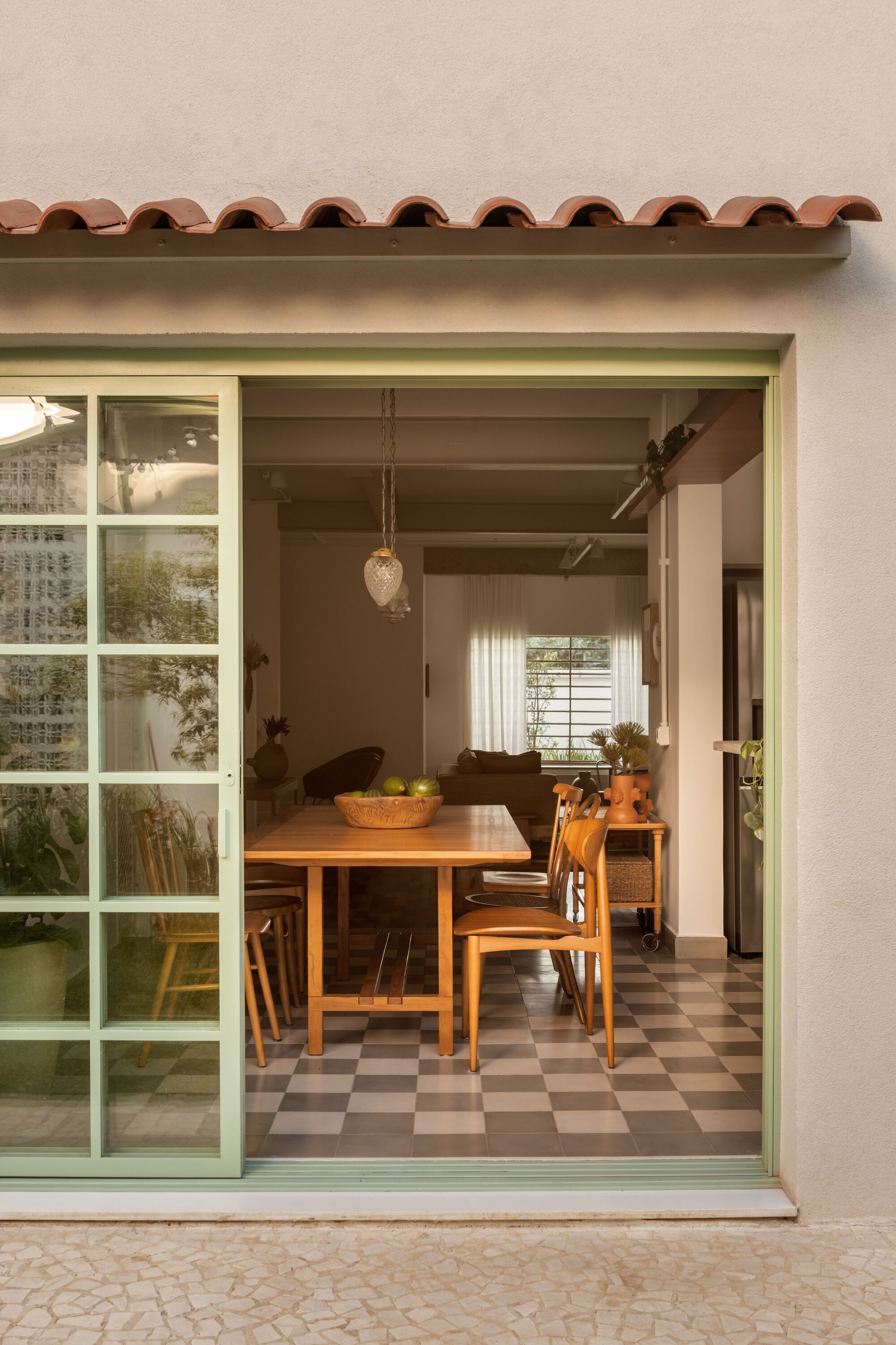 View through pale green sliding door to dining room with terracotta tile awning detail above