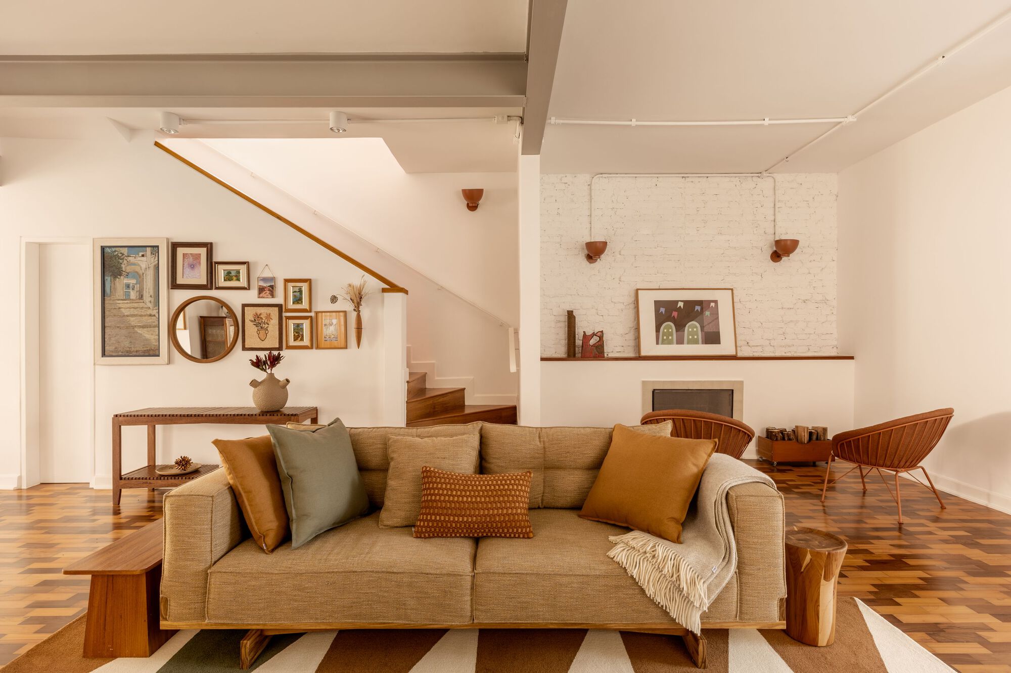 Living room with geometric patterned floor and staircase ascending behind a gallery wall