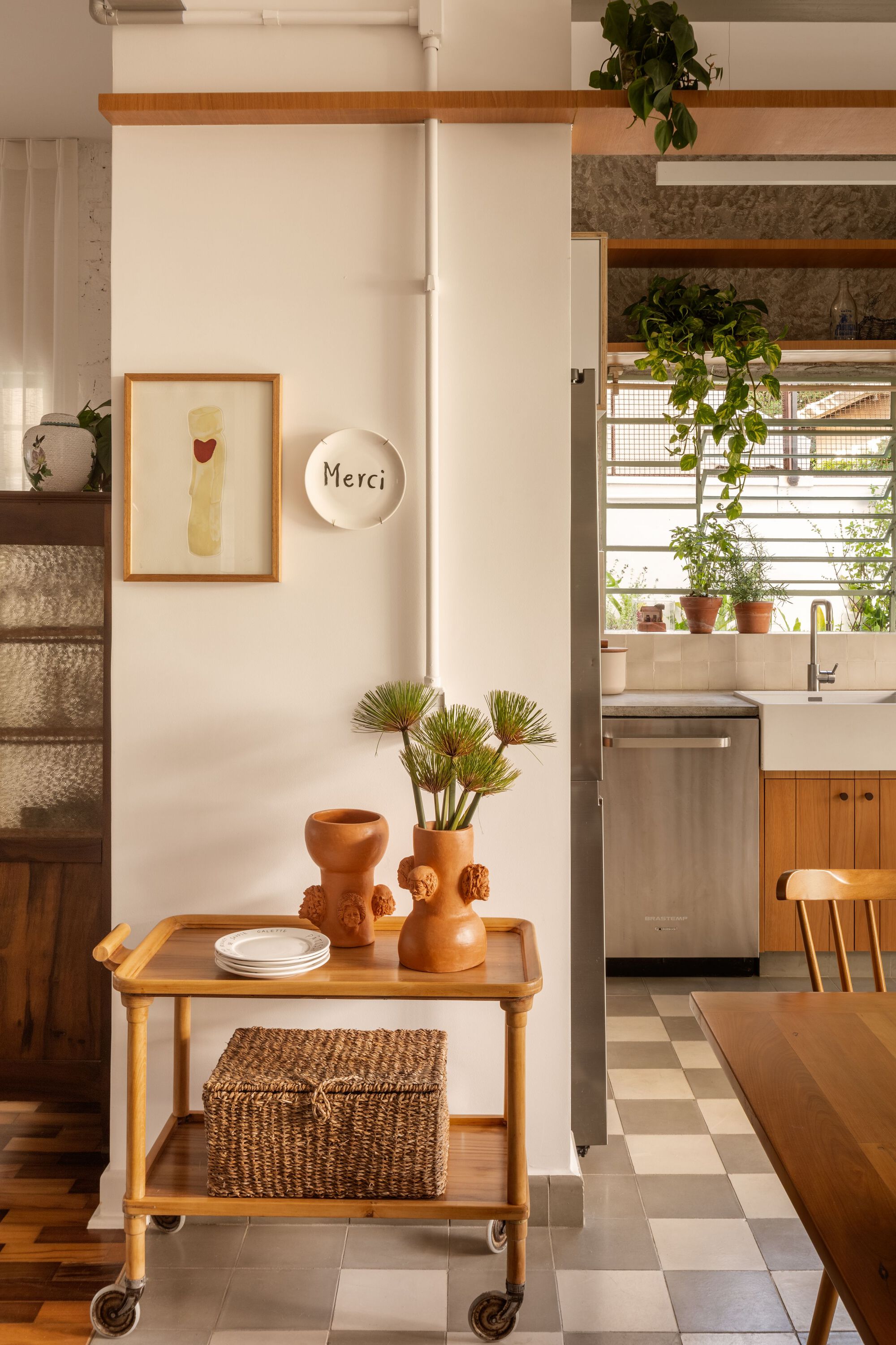 Kitchen entry with rolling cart and checkered floor beside climbing plants on windowsill