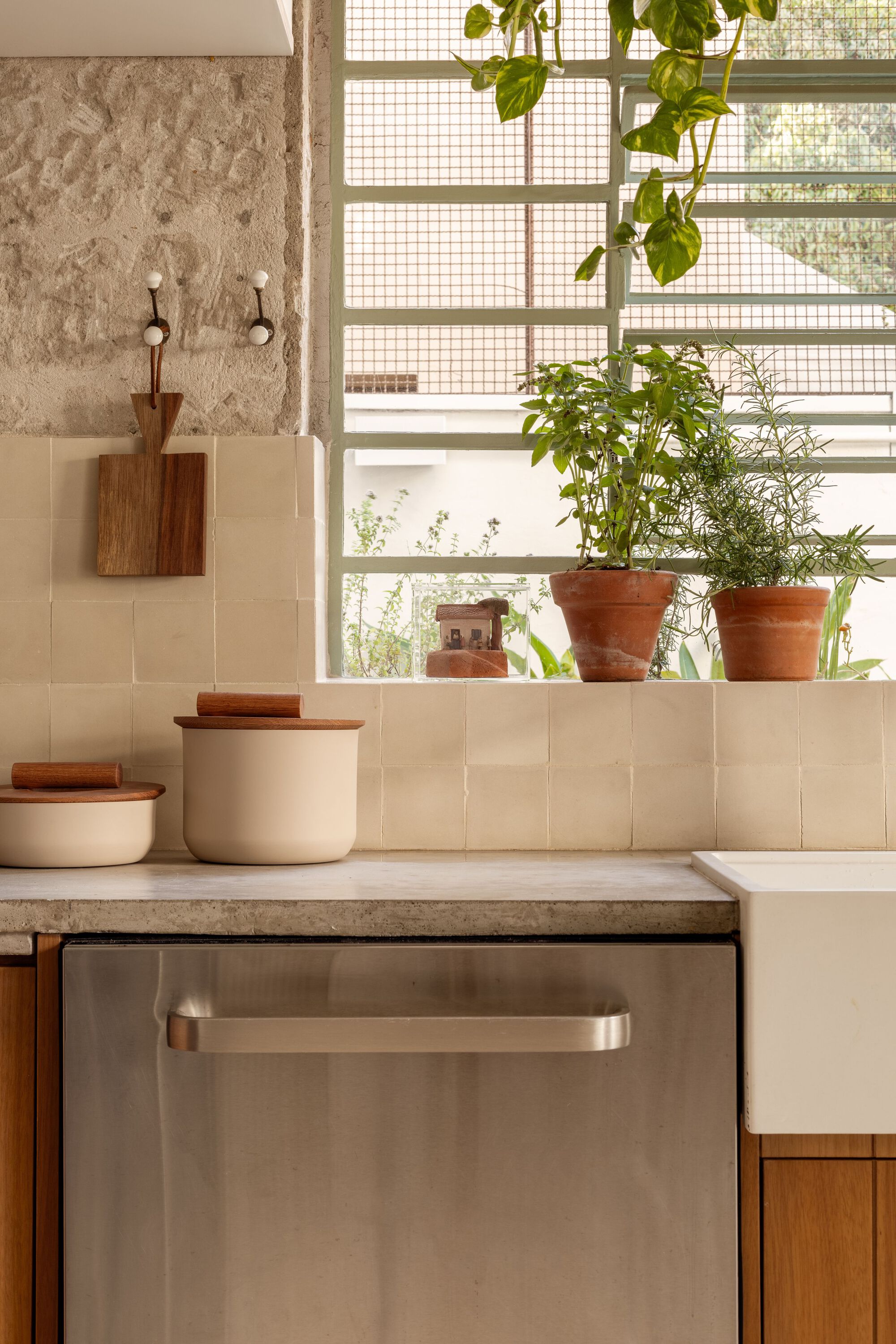 Kitchen counter with cream tile backsplash, terracotta plant pots on the ledge, and gridded glass block window