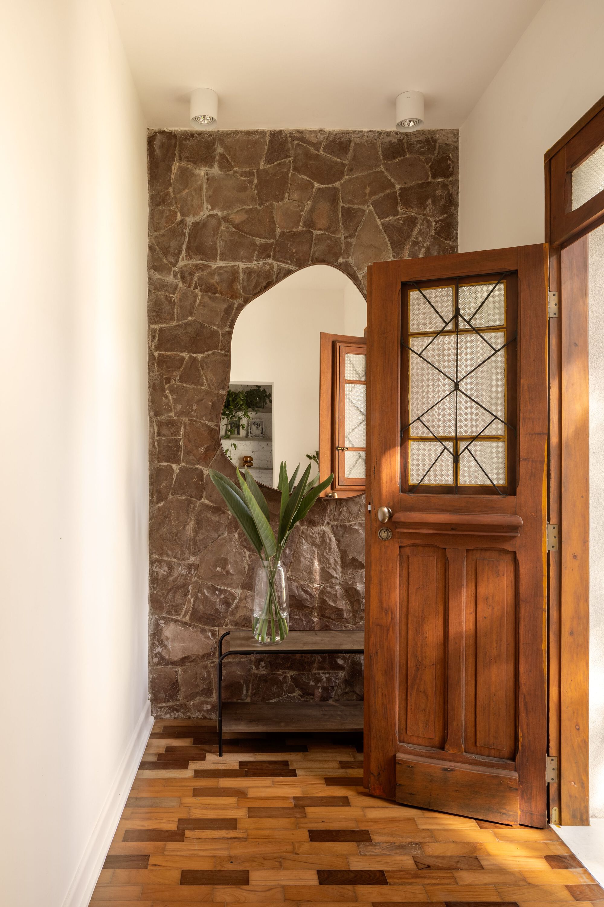 Entry hall with timber door opening to brown stone wall and arched passage beyond