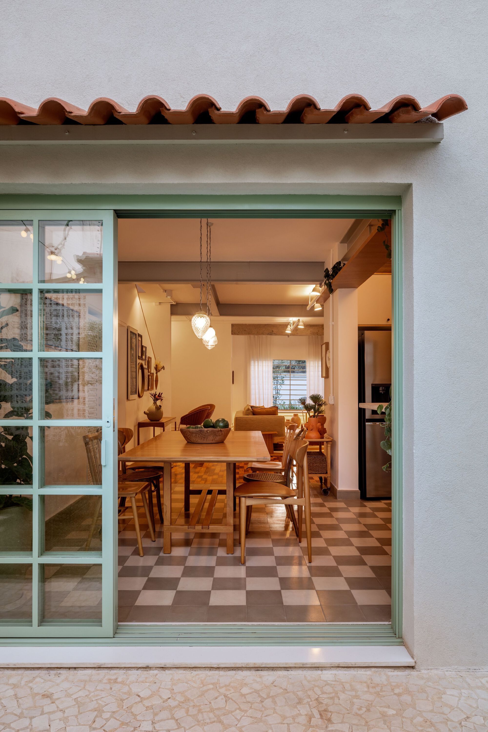 View through mint green sliding doors to dining room with exposed timber beams at dusk
