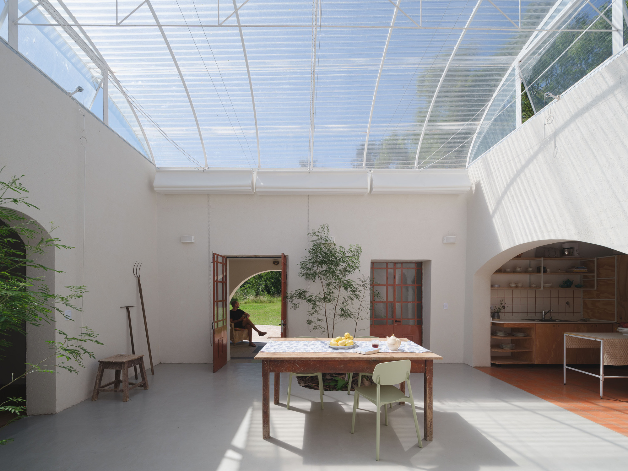 Interior courtyard with translucent arched roof, dining table and planted beds on polished concrete floor
