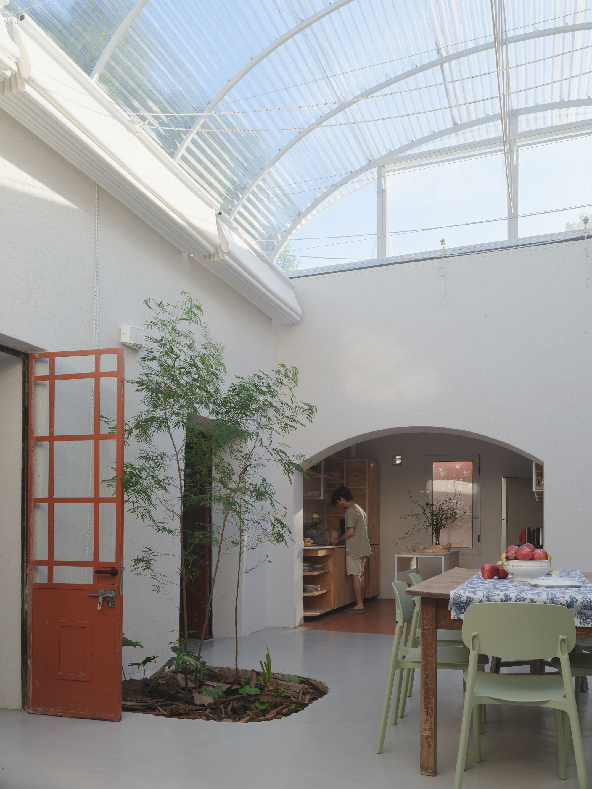 View through terracotta glazed door toward kitchen opening beneath the translucent barrel vault ceiling