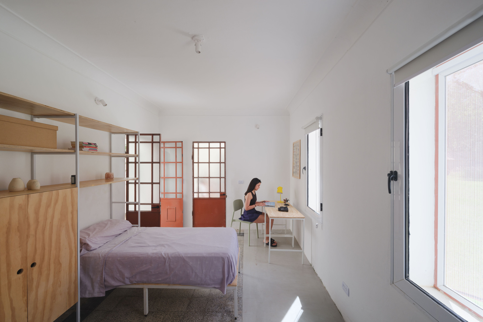 Bedroom interior with red and brown gridded glass partitions and a person working at a desk