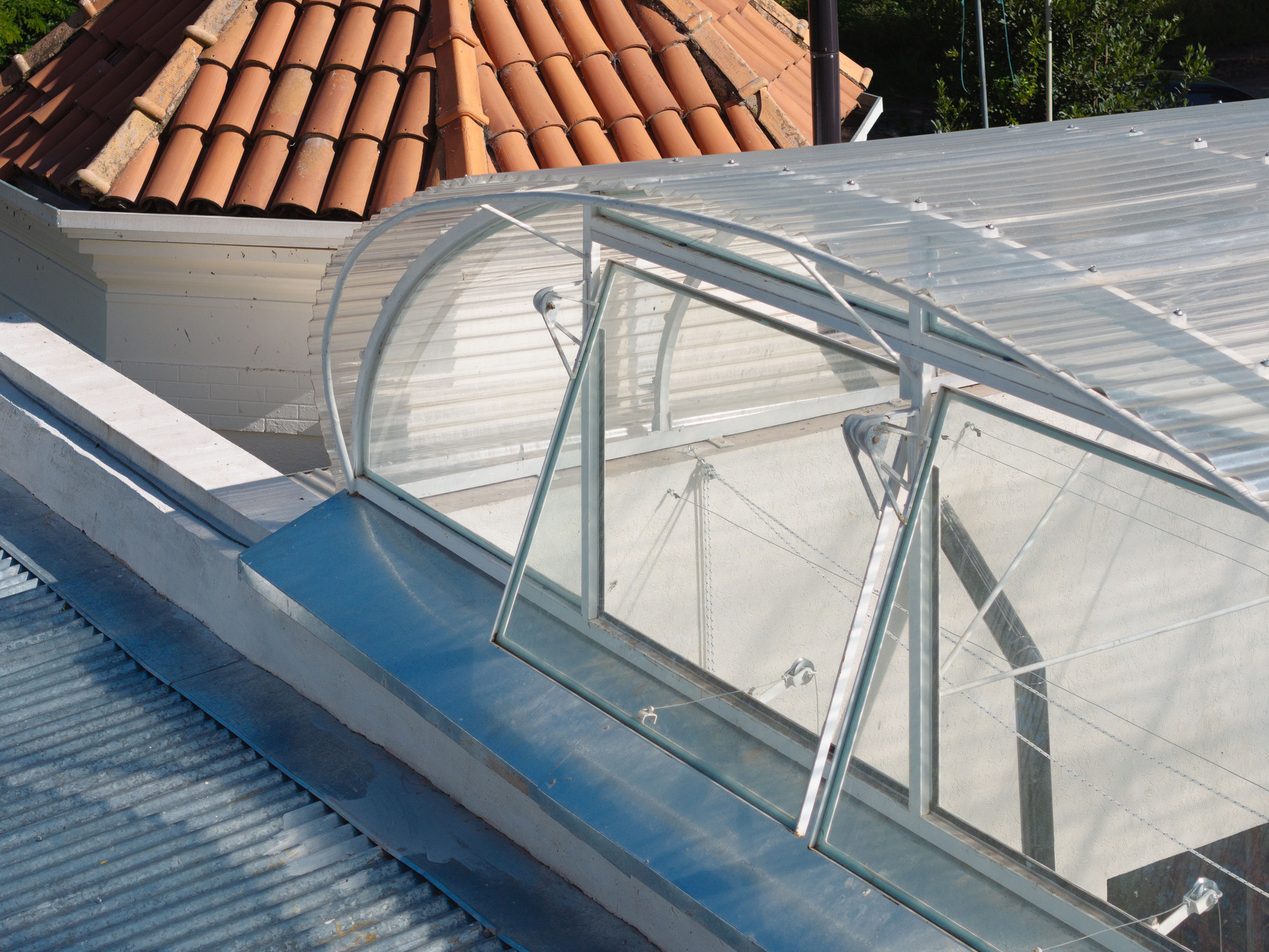 Rooftop view of the arched translucent skylight atop corrugated metal sheeting beside the tiled dome