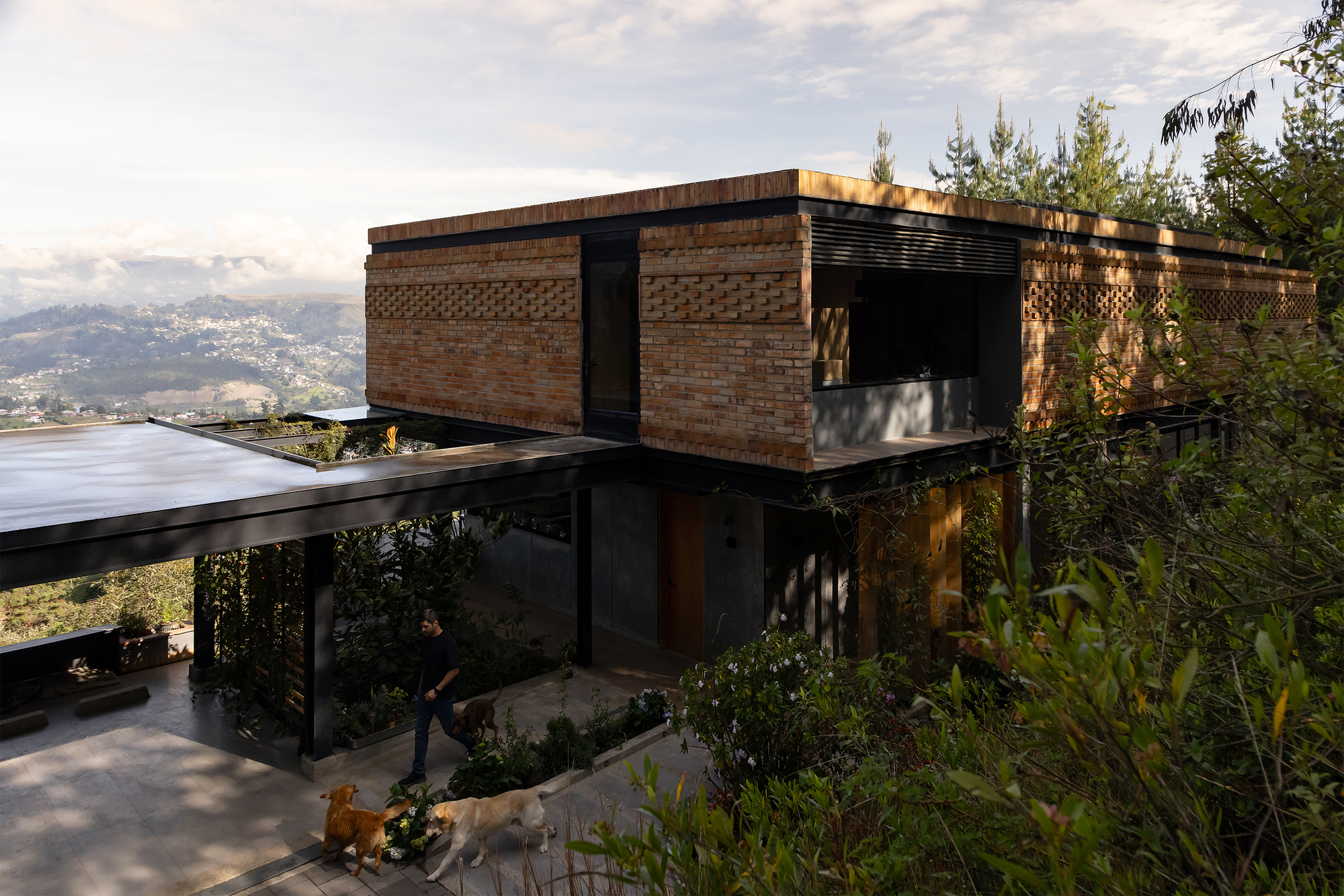 Brick-clad upper volume with patterned masonry panels cantilevering over a glazed lower level