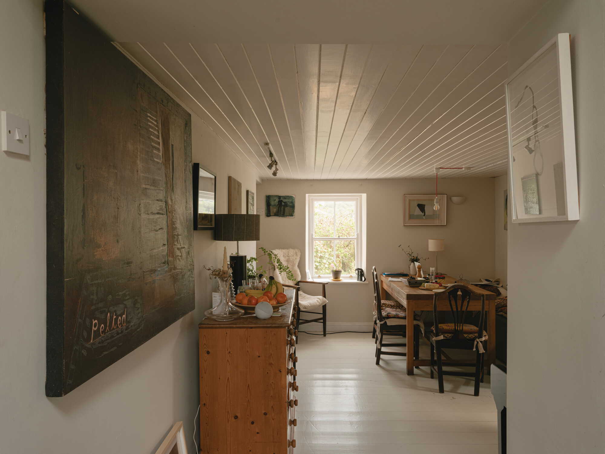 Open kitchen and dining area with tongue-and-groove ceiling and whitewashed floorboards