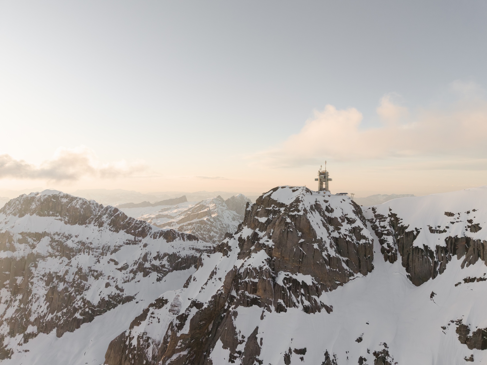 Observation structure with white mast perched atop a rocky summit at sunrise