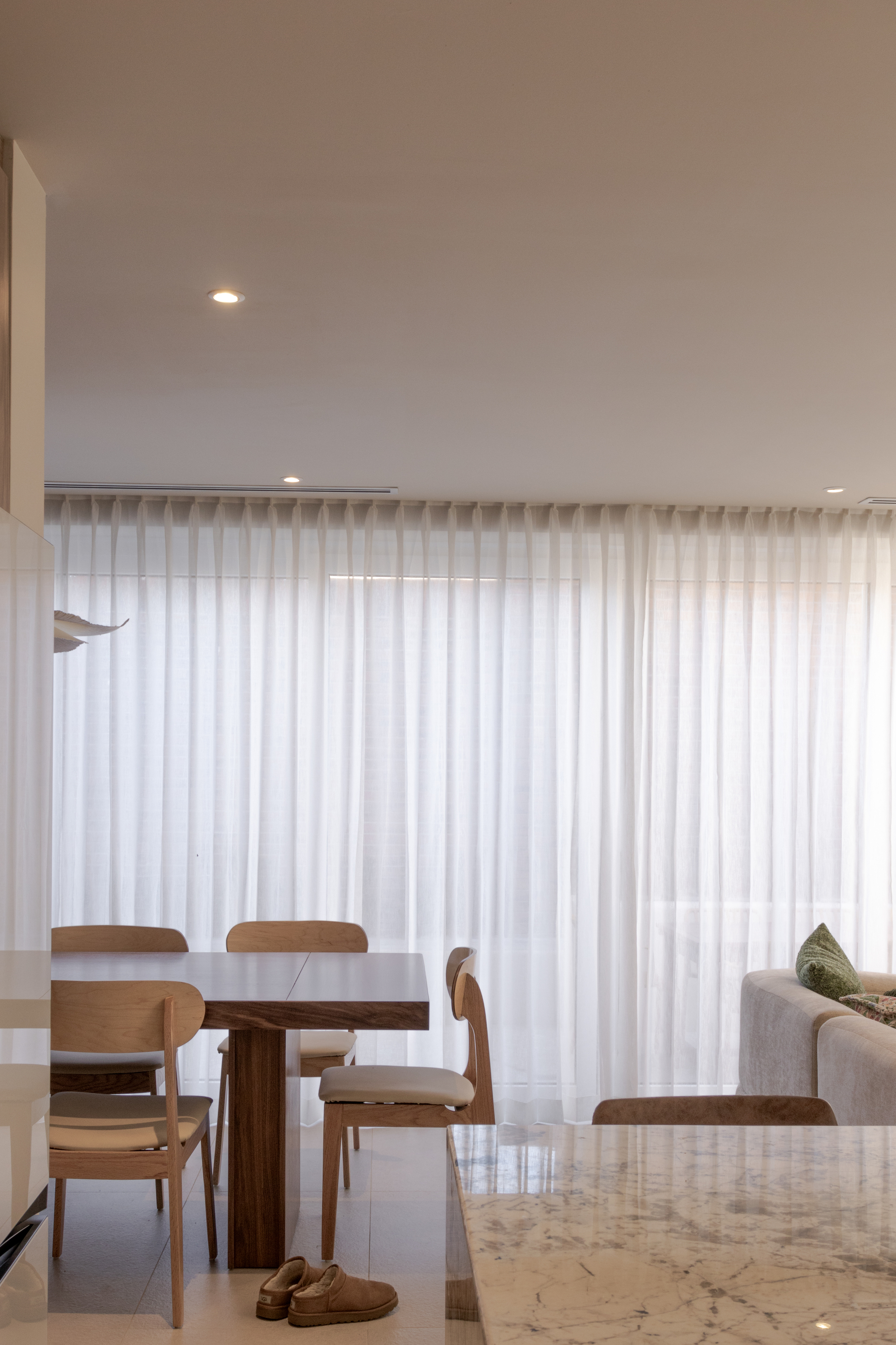 Living and dining area with marble countertop edge and full-height sheer curtains