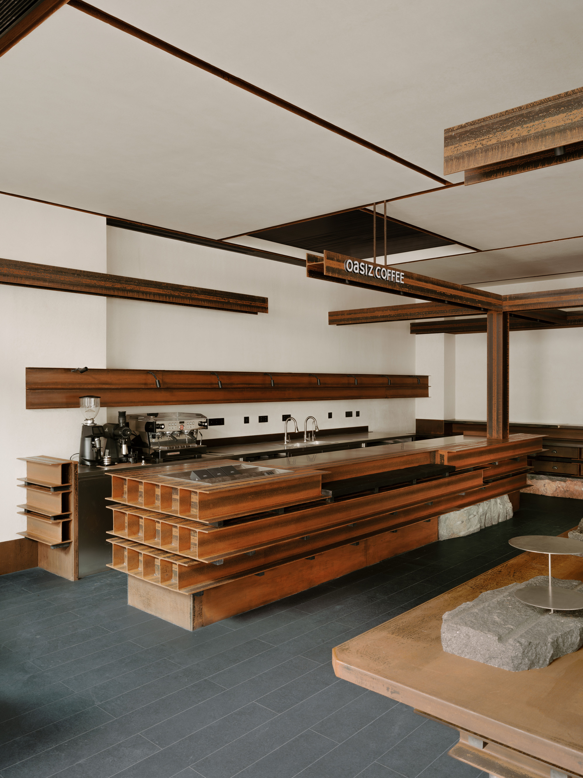 Coffee bar with stacked timber counter and stone-topped seating under exposed wood beams