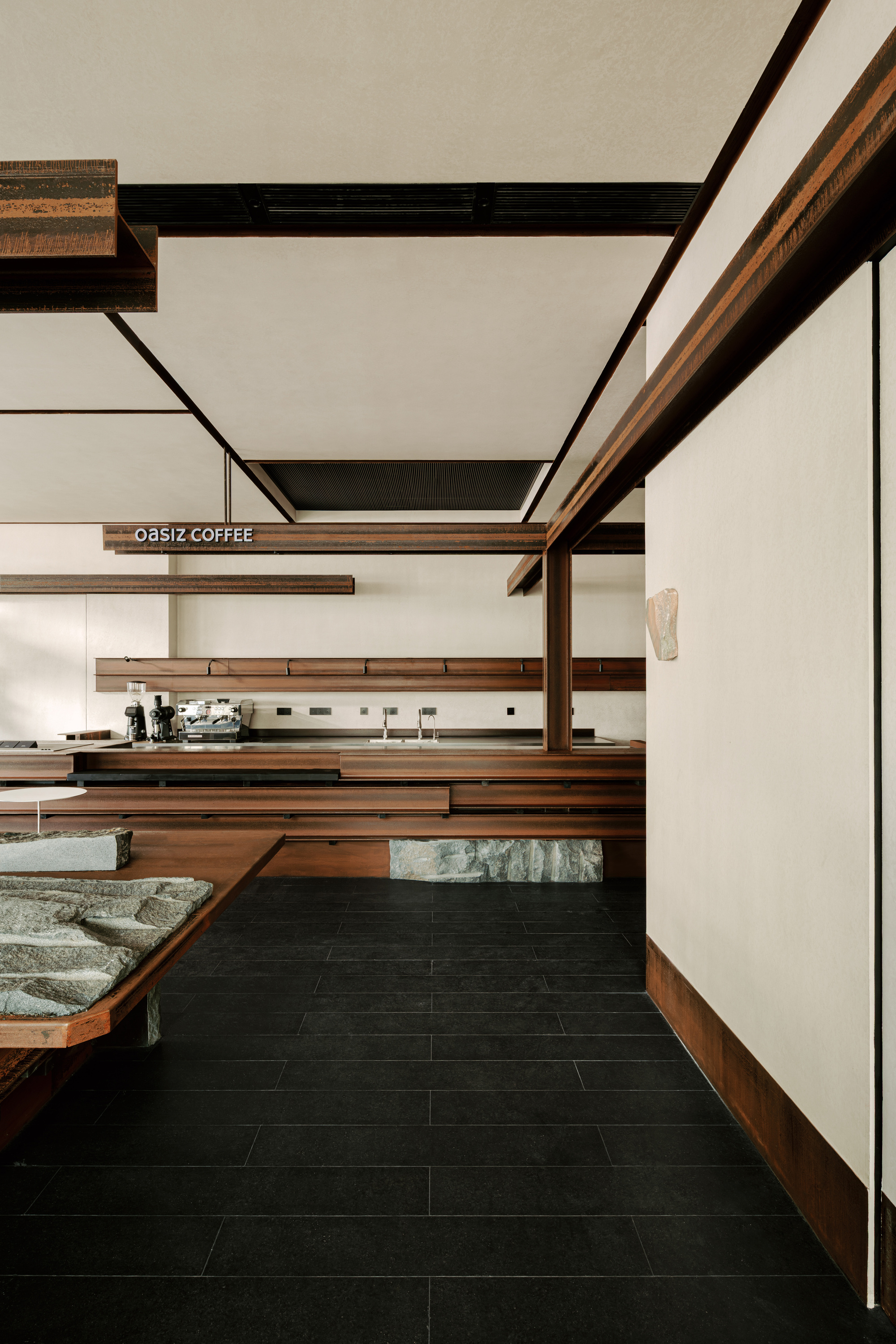 Coffee service counter with horizontal timber shelving and exposed beam ceiling above dark floor tiles