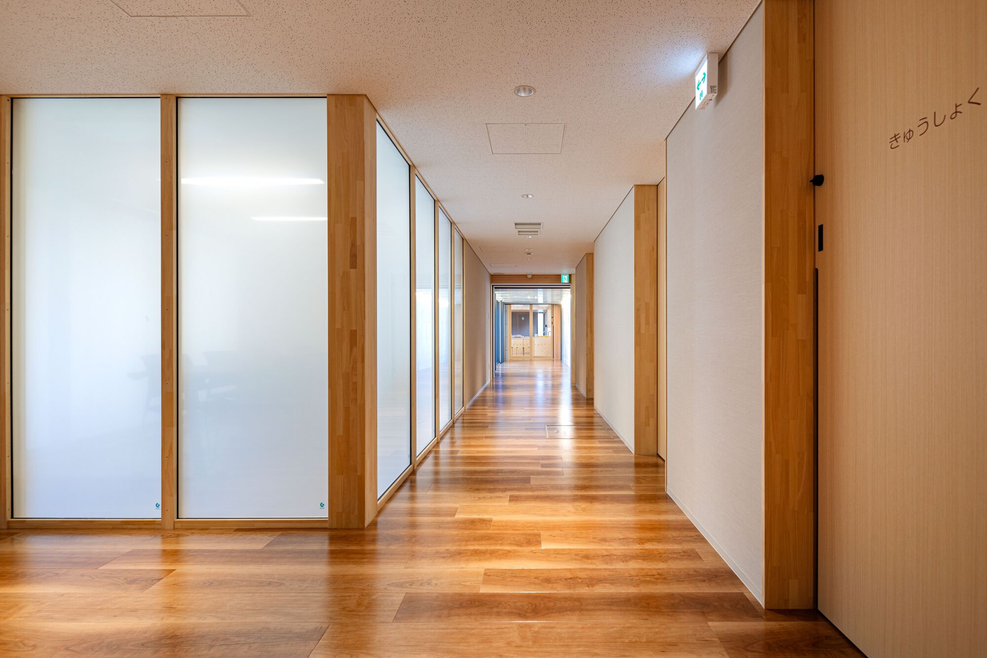 Interior corridor with translucent timber-framed partitions and wood doors along a smooth wood floor