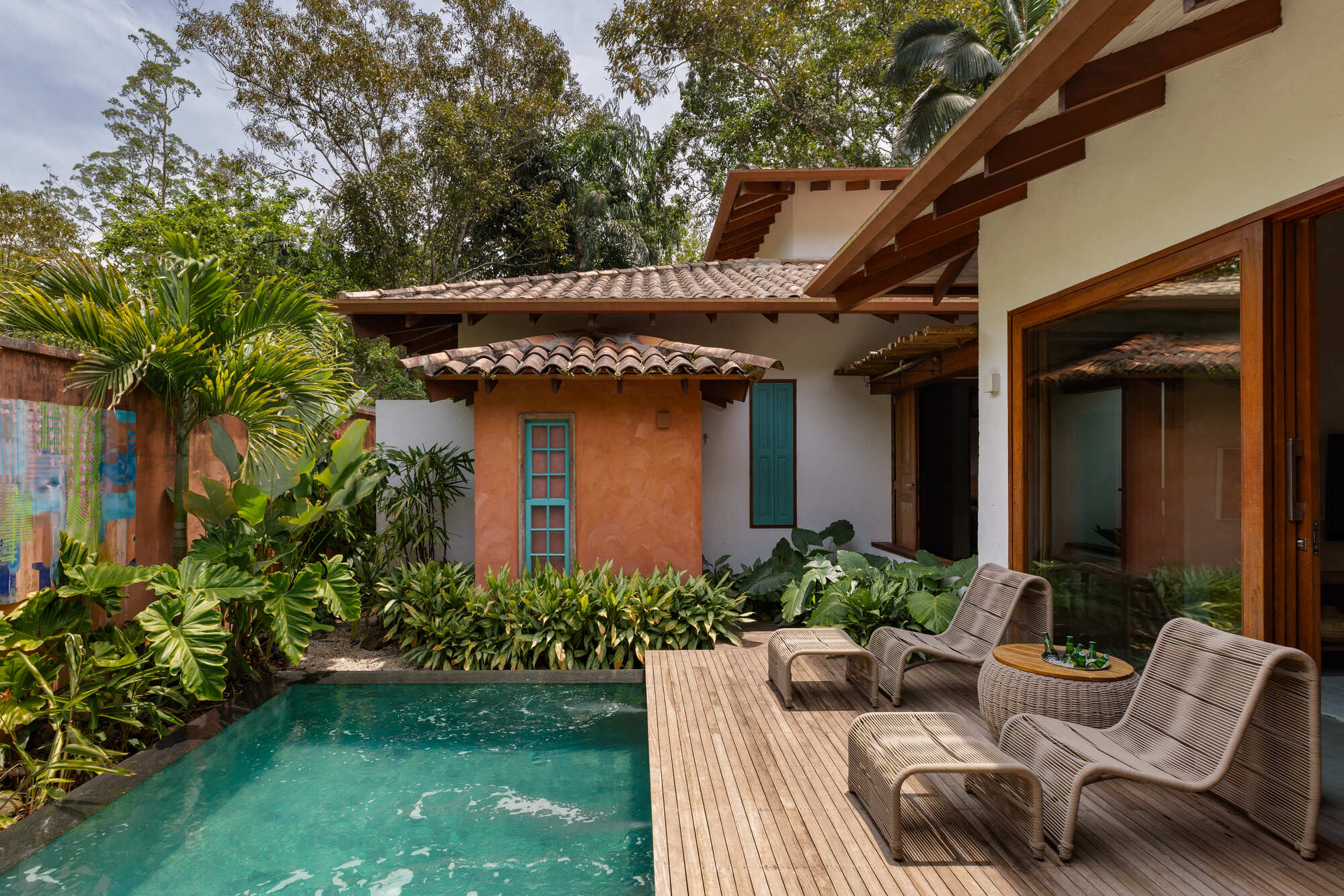 Timber deck surrounding small pool with lounge chairs facing ochre and white stucco walls