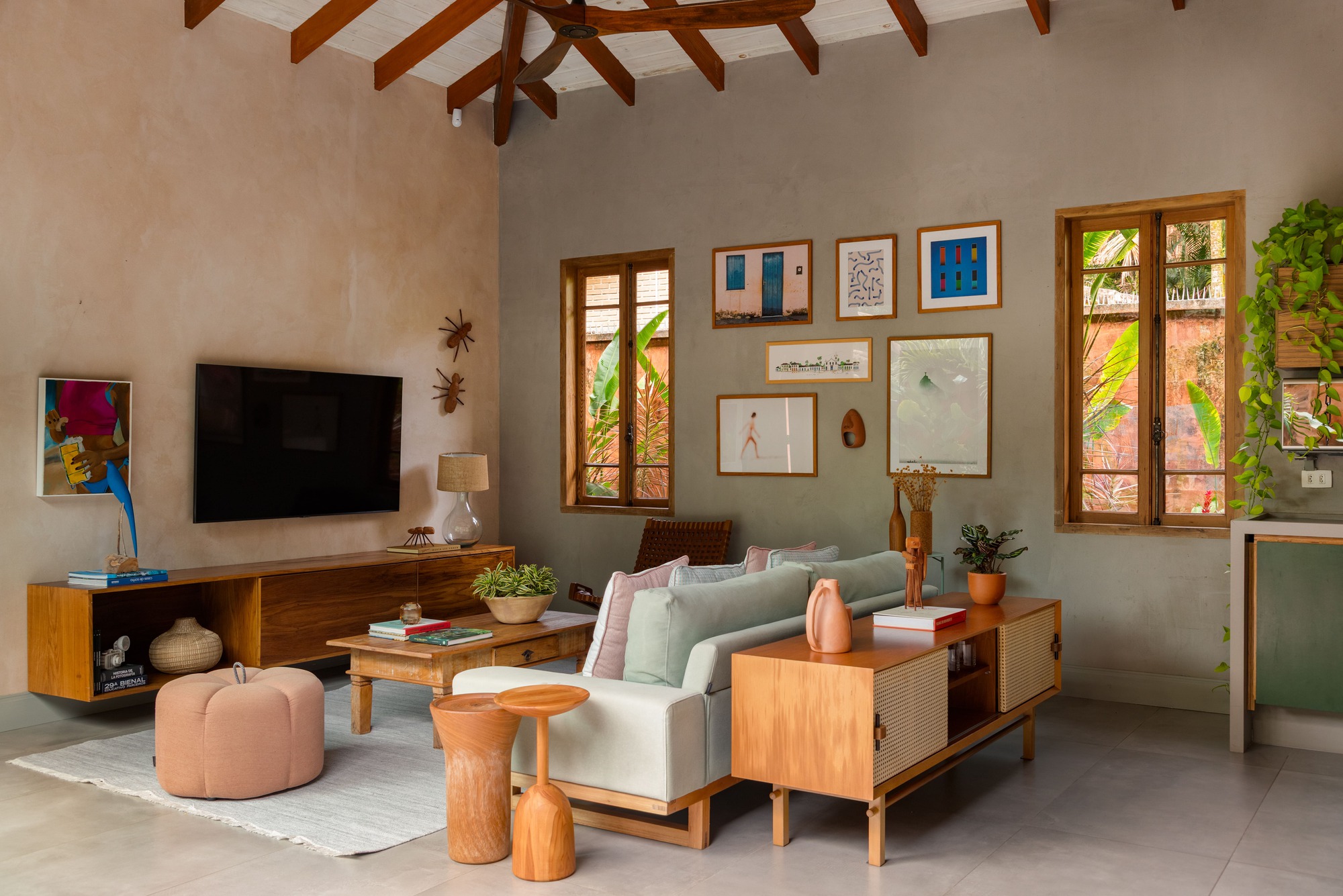Living room with exposed timber trusses, gallery wall of framed art, and terracotta tile floor