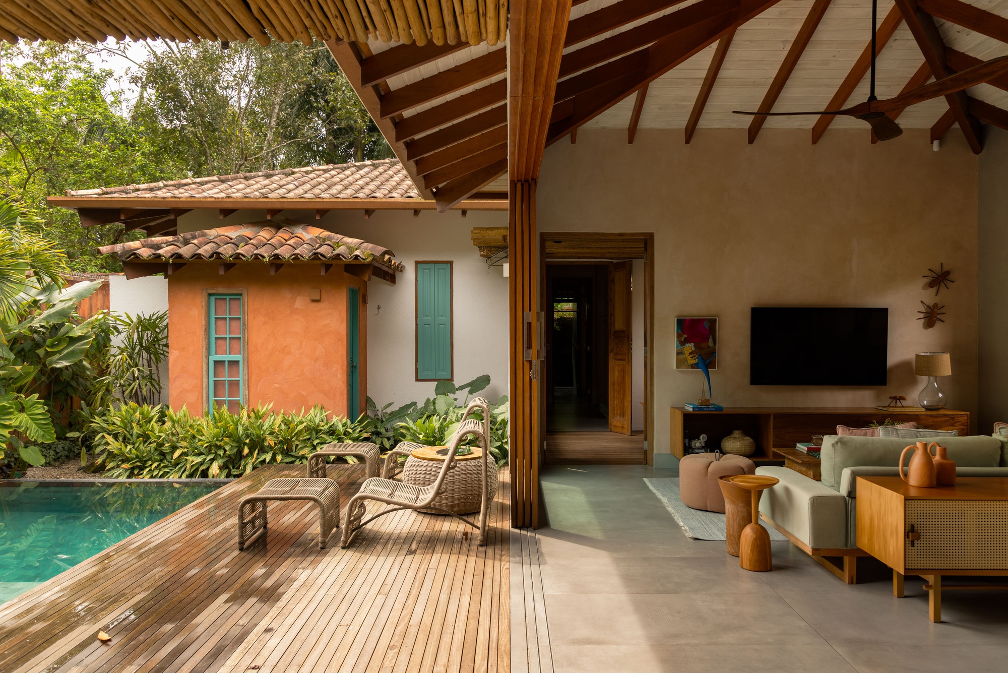 Open living pavilion with slatted timber canopy extending over pool deck and planted courtyard