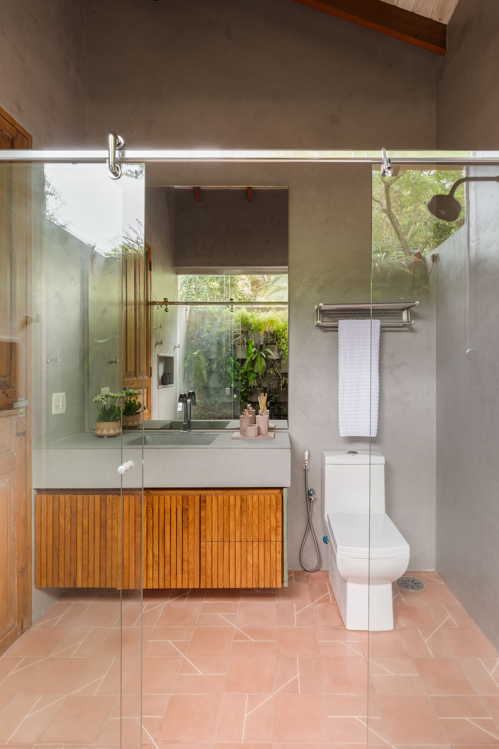 Bathroom vanity with slatted timber cabinet and sliding glass partition beneath exposed timber ceiling