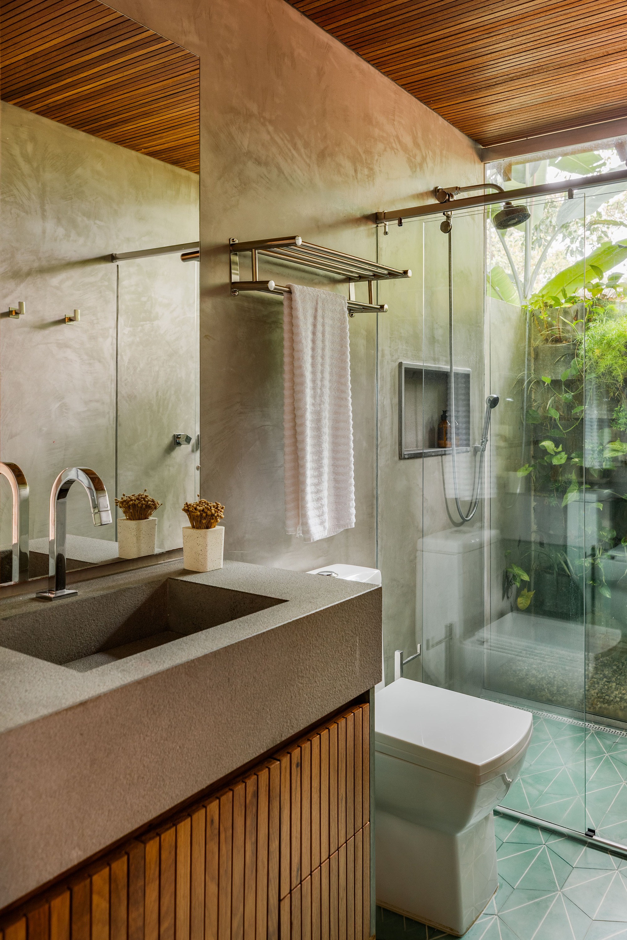 Bathroom with timber slat ceiling, terrazzo vanity and glass shower enclosure overlooking green courtyard