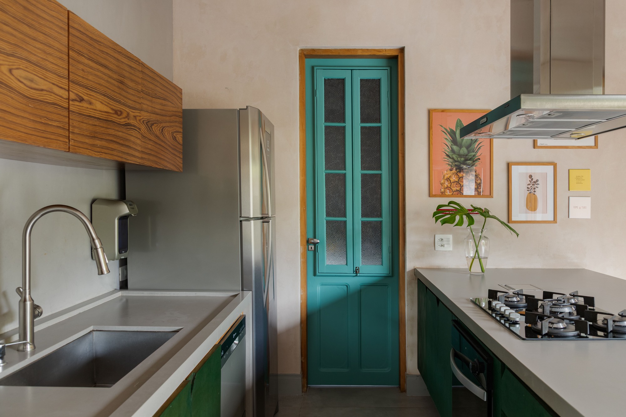 Turquoise paneled door with glazed upper section set between wooden cabinetry and green lower units