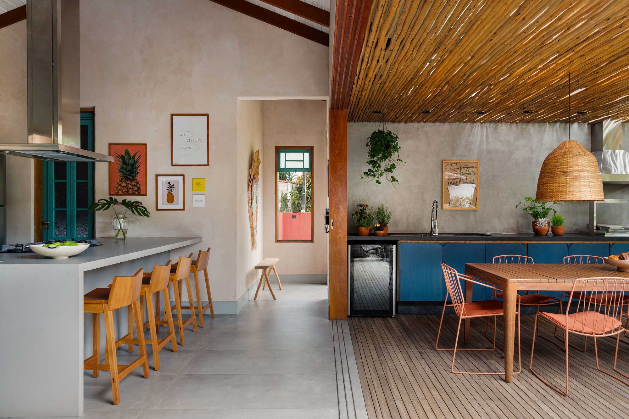 Open kitchen and dining area with slatted timber ceiling overhang and concrete floor transitioning to timber deck