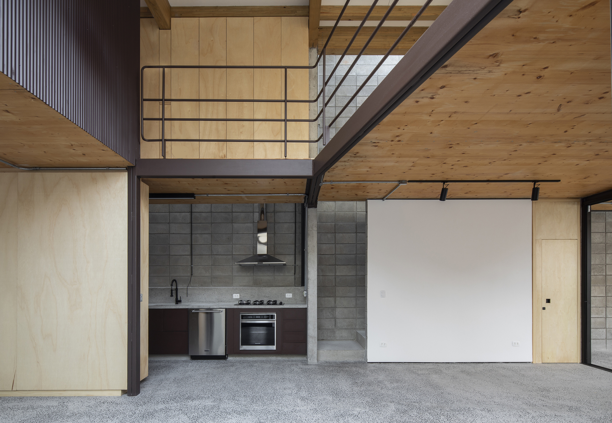 Double-height kitchen with exposed timber beams and grey concrete block wall