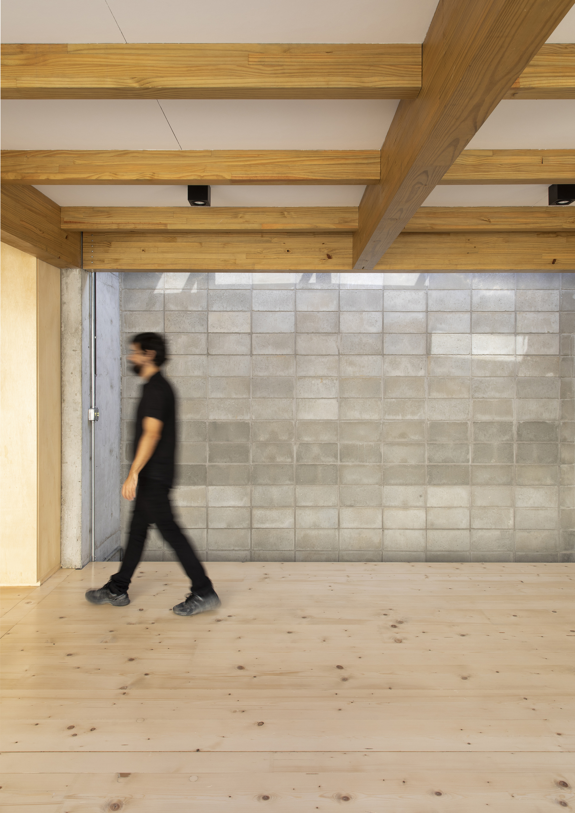 Interior hallway with concrete block wall and a figure walking across timber flooring