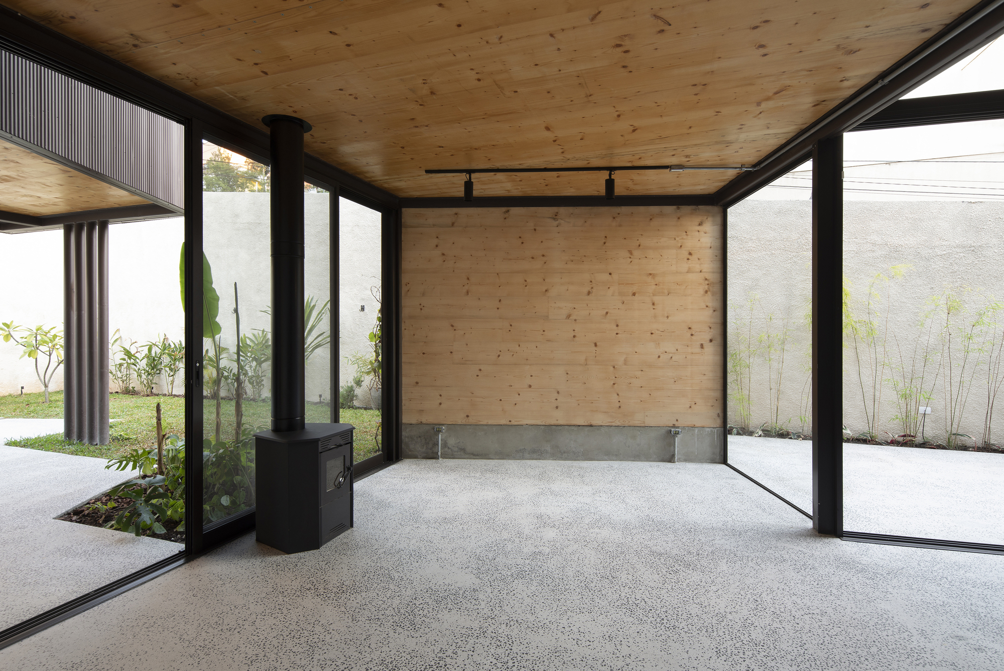 Interior corner with plywood wall, concrete block base and steel-framed glazing overlooking landscaped courtyards