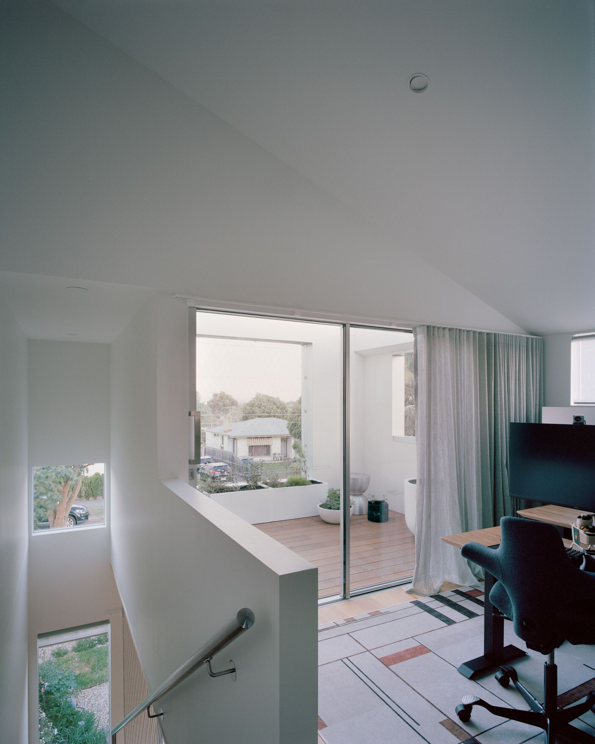 Upper landing with white walls and sliding glass doors opening to a timber balcony