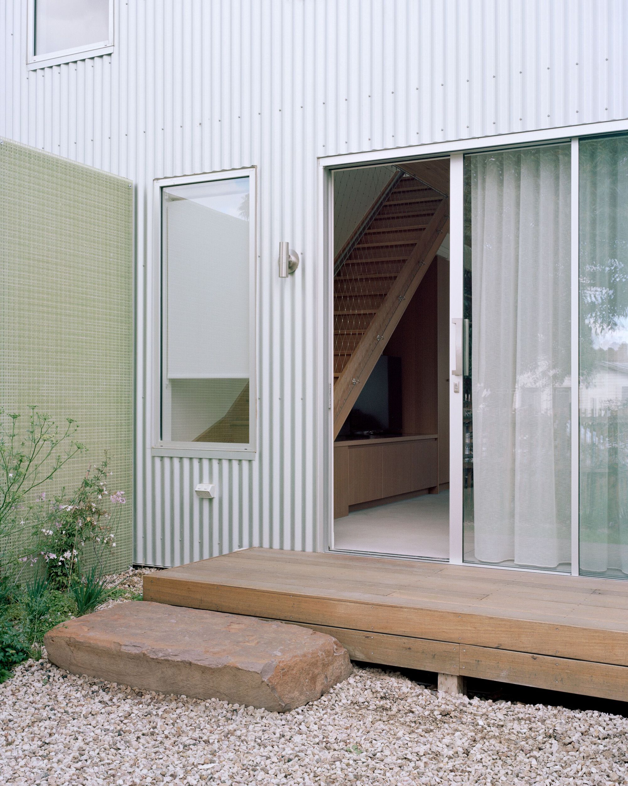 Timber deck threshold with sandstone step leading through sliding glass doors into the interior