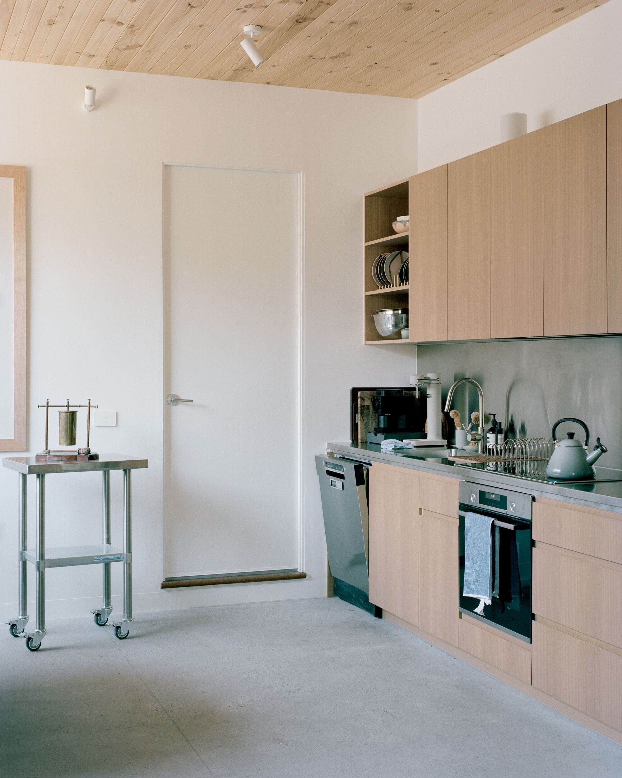 Kitchen with pale timber cabinetry and exposed timber ceiling above polished concrete floor