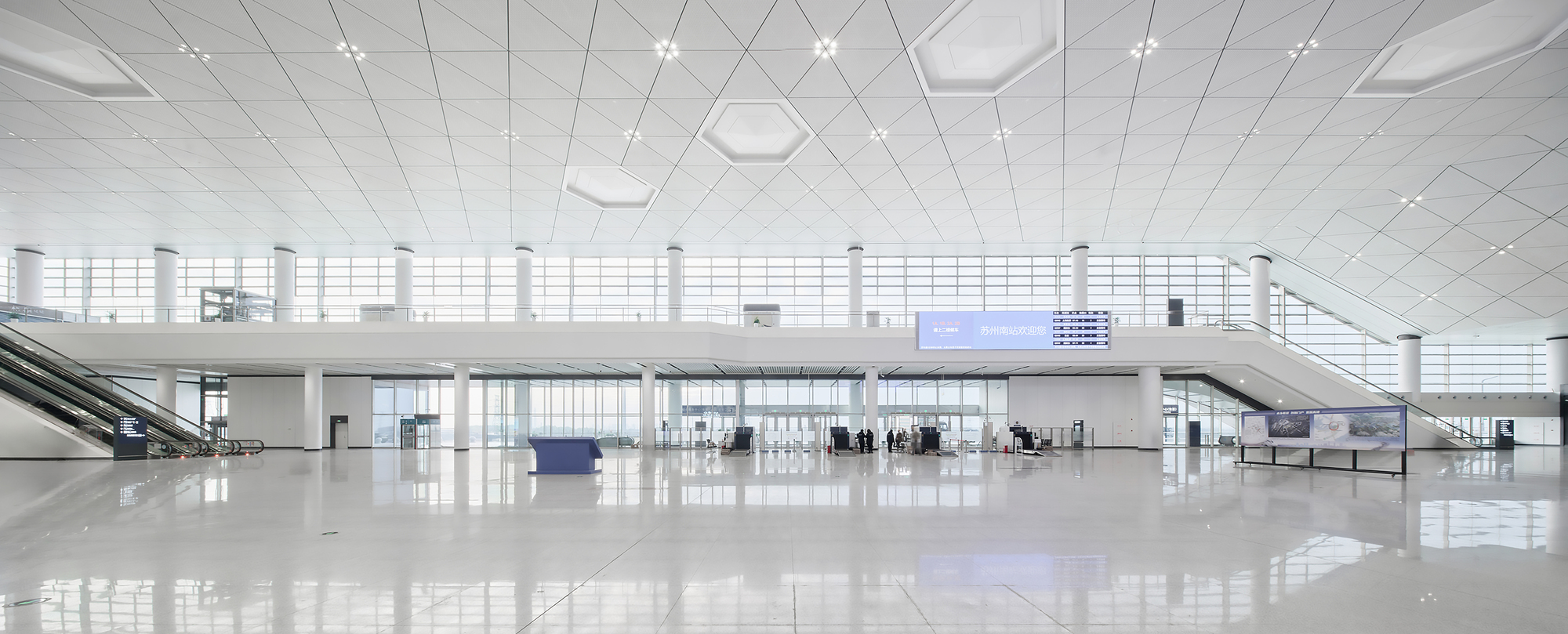 Interior departure hall with white tile ceiling, mezzanine level and passengers near service counters